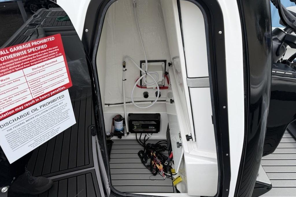 Interior view of 2026 Tidewater 2500 Carolina Bay boat compartment with equipment and warning signs.