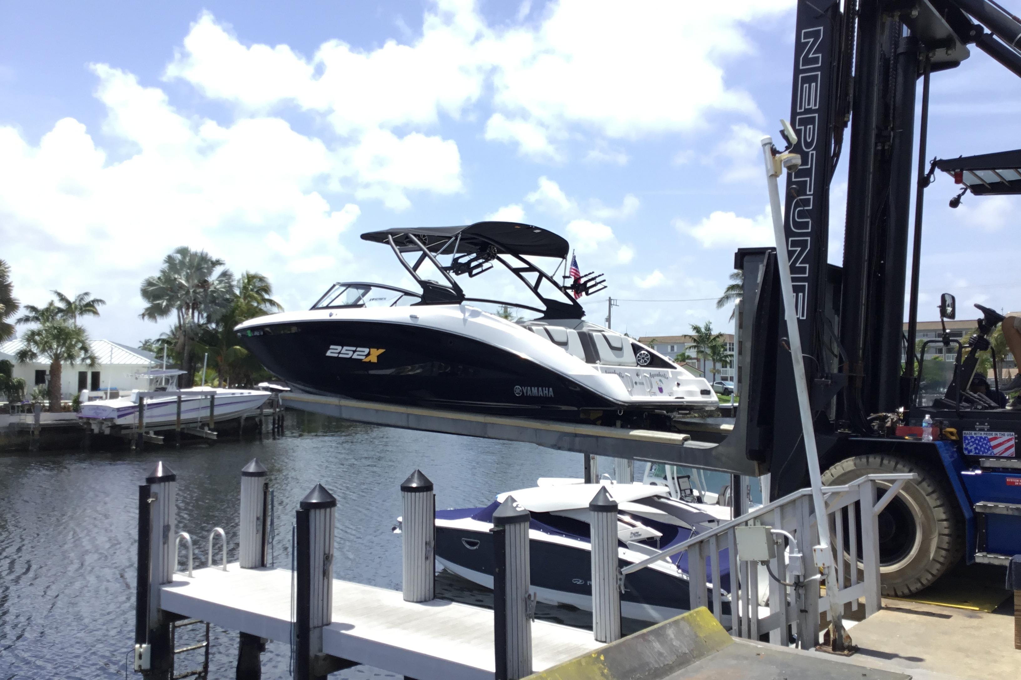 2023 Yamaha Boats 252XE being lifted by a forklift at a marina.