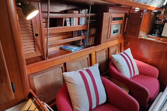 Cozy interior of 1984 Bristol 45.5 Center Cockpit with red chairs and wooden shelves.
