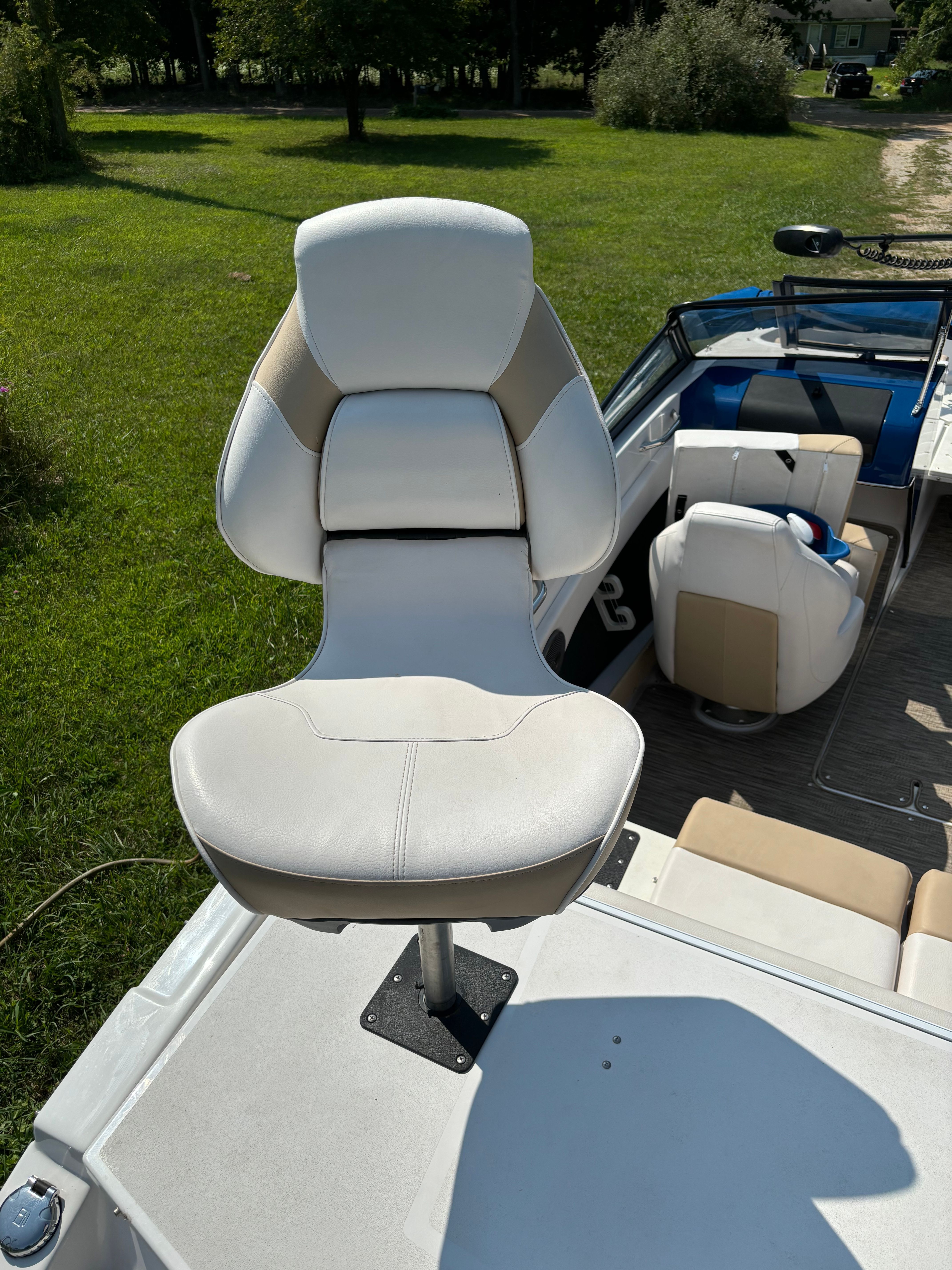 A Glastron GTSF 185 boat with a white seat on green grass.