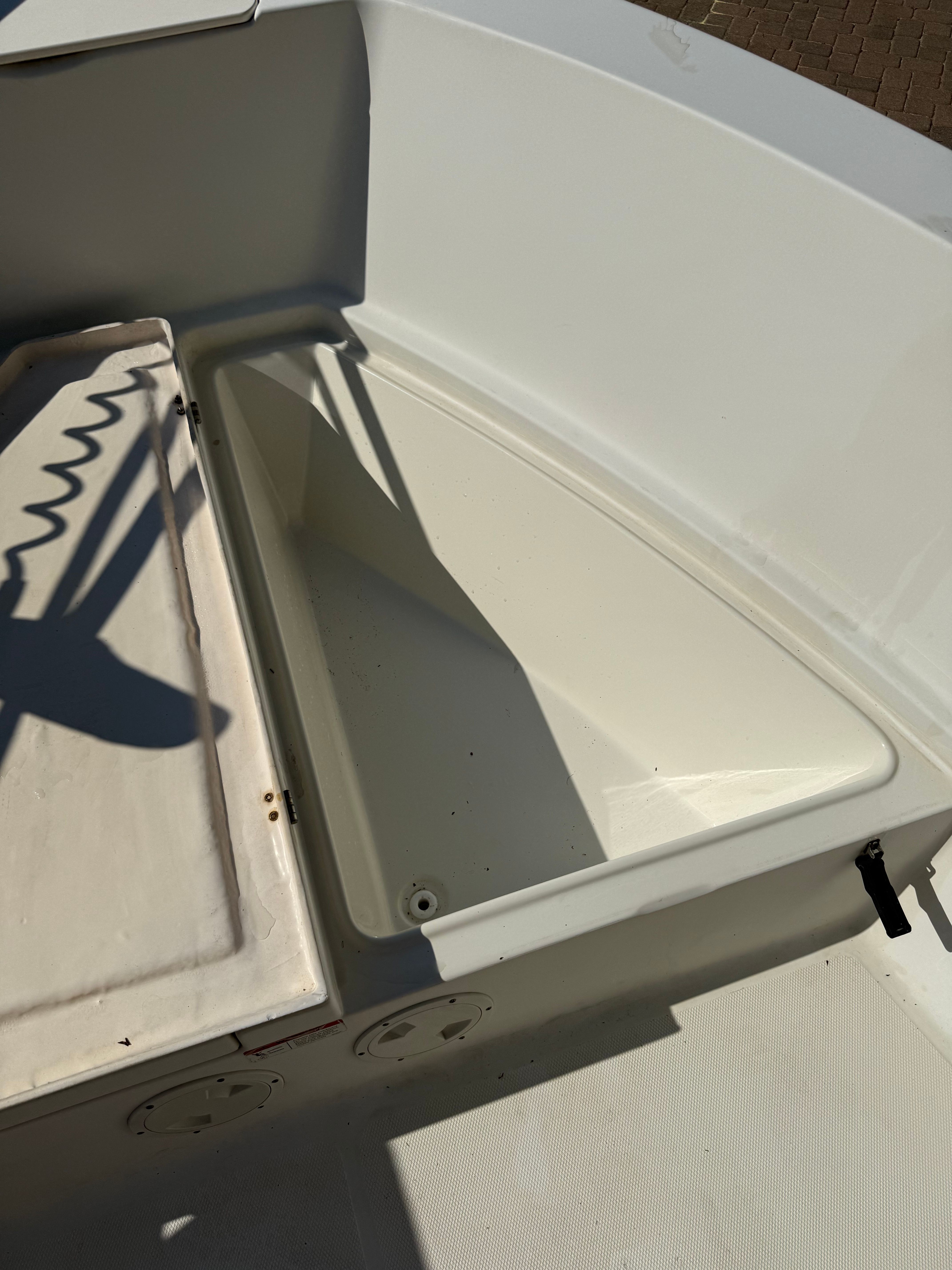 An open storage compartment on a boat with white surfaces.