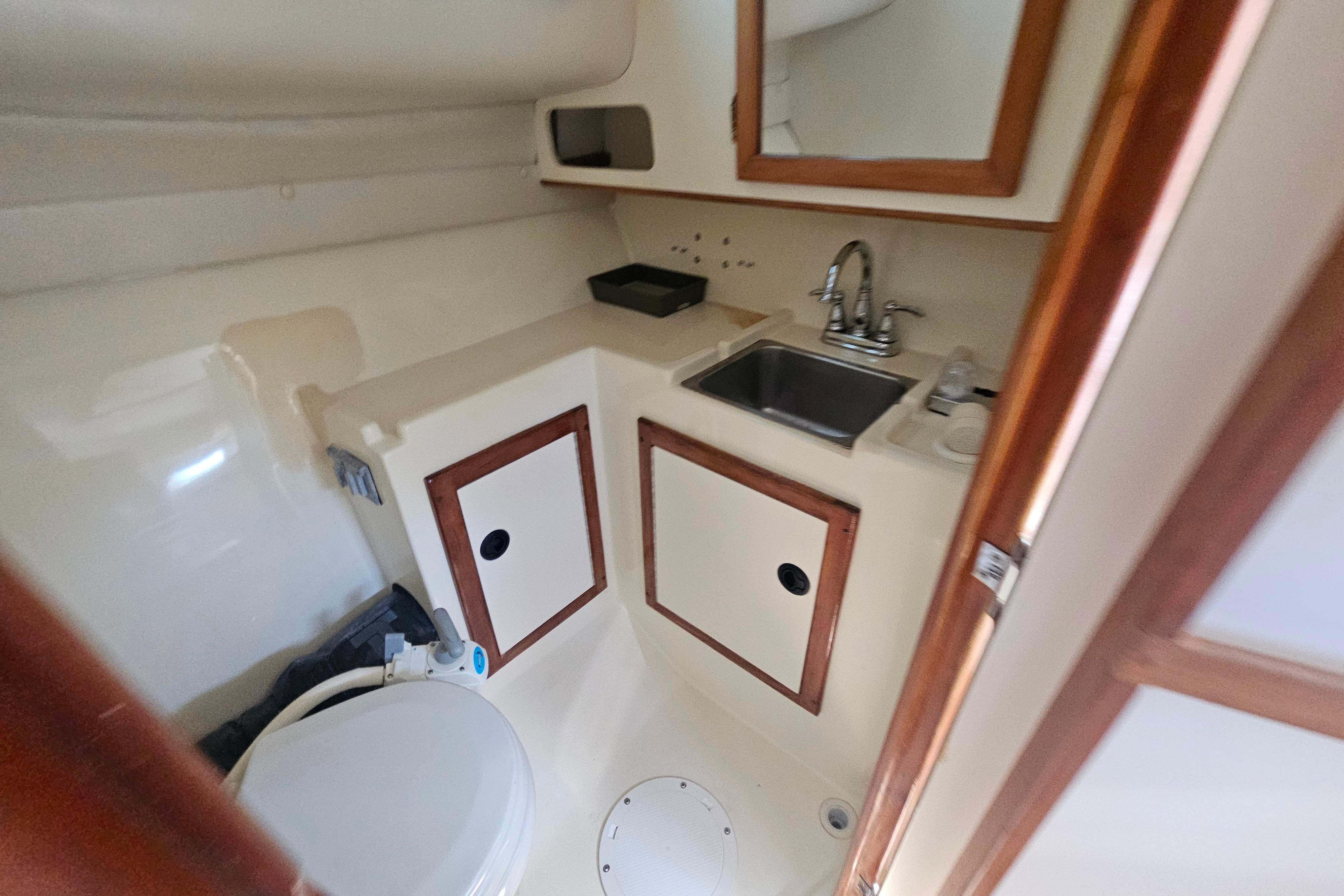1999 Albin 28 Tournament Express boat bathroom with sink, mirror, and storage cabinets.