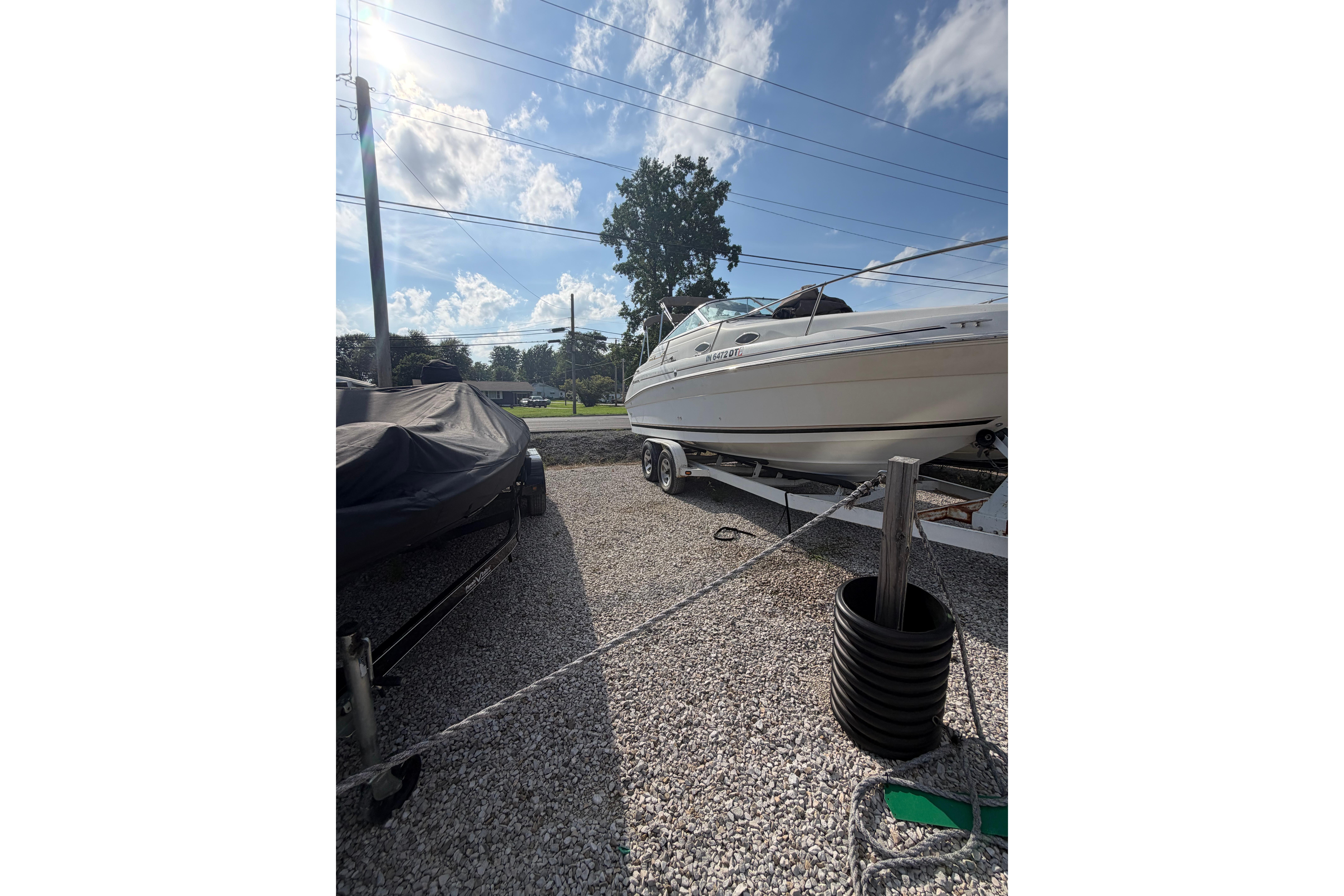 1999 Sea Ray 240 Sundancer boat on trailer under clear blue sky.