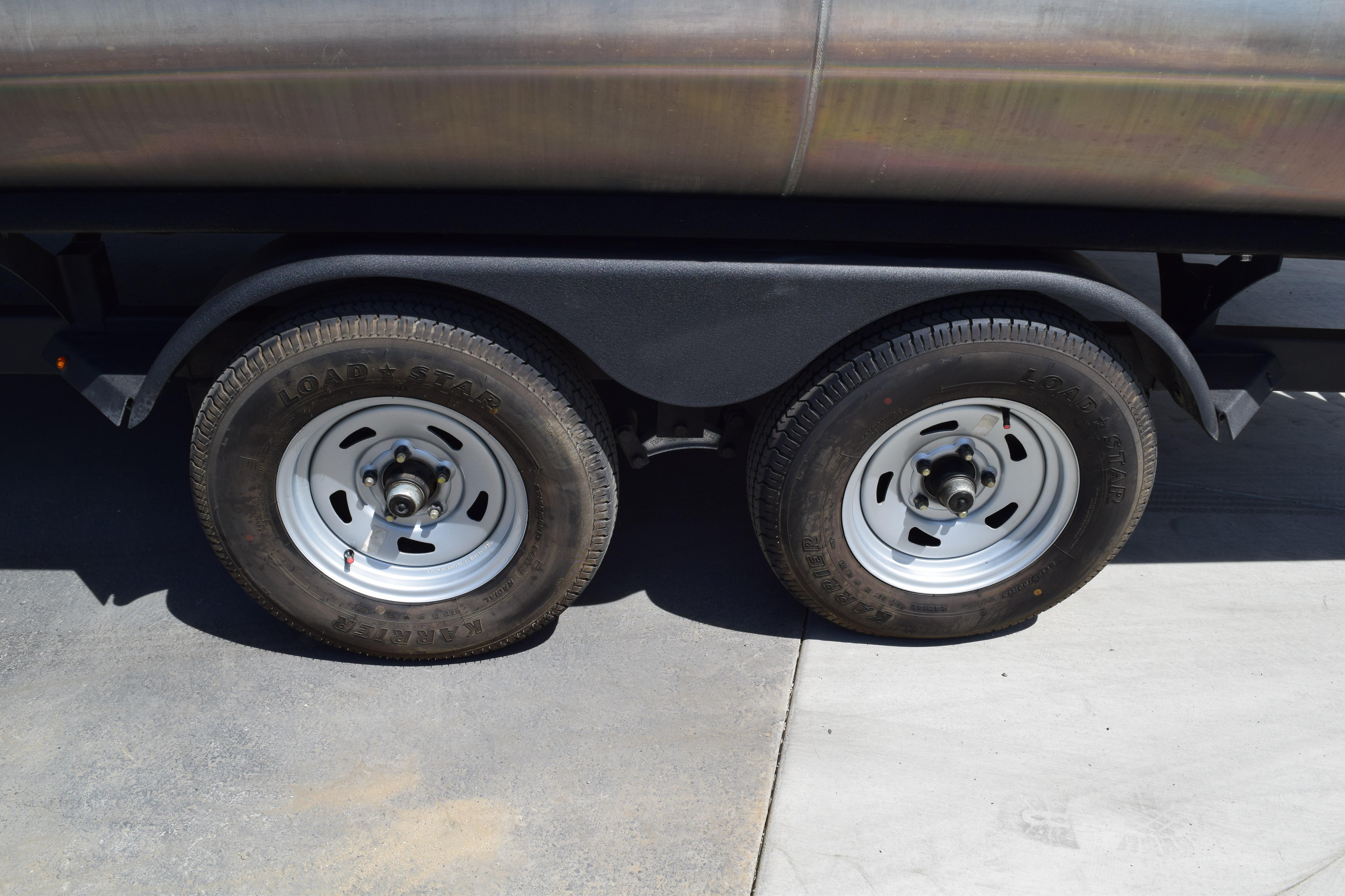 Trailer wheels of a 2025 Sun Tracker Party Barge 22 XP3 on pavement.