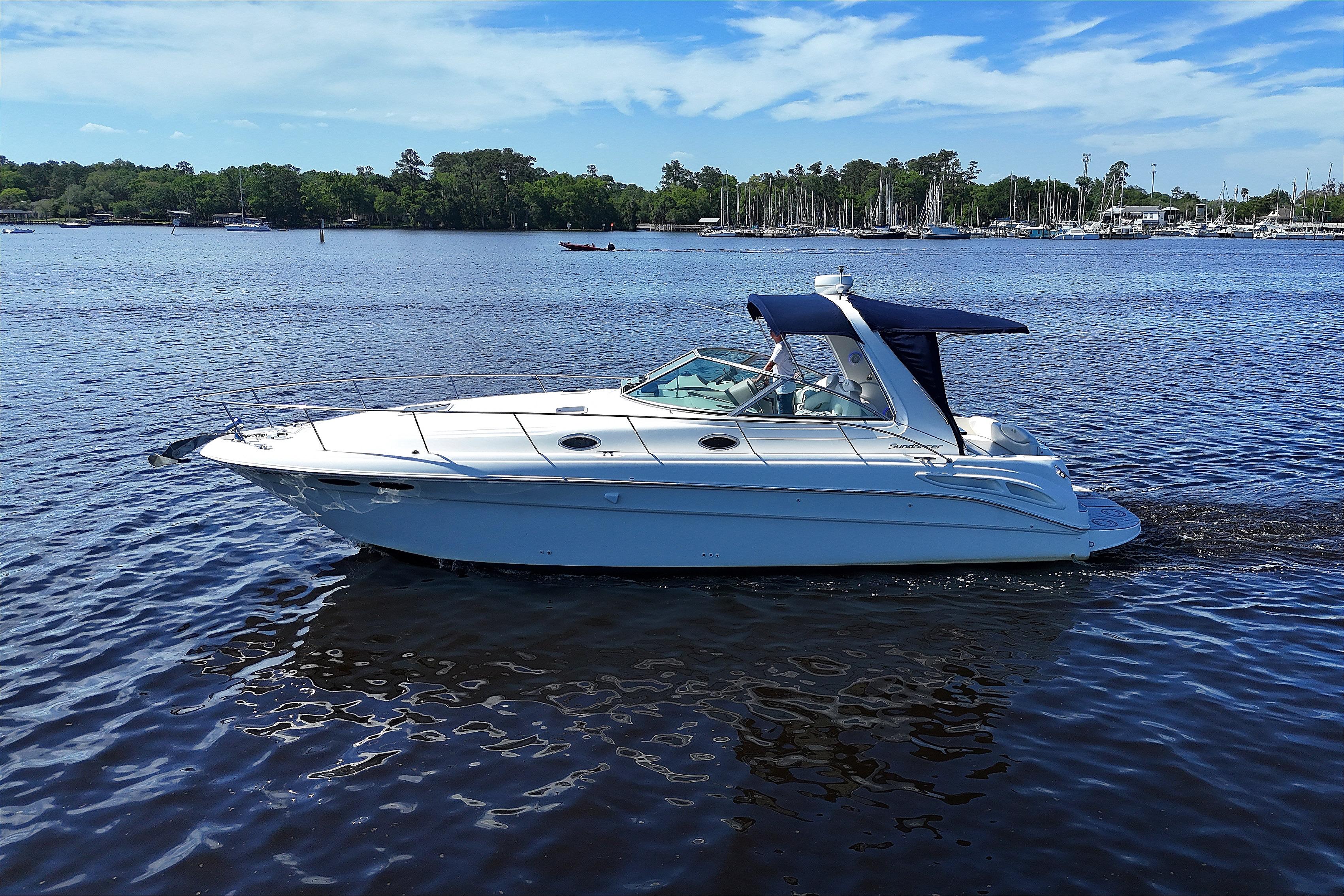 2001 Sea Ray 340 Sundancer cruising on a serene lake under a clear blue sky.