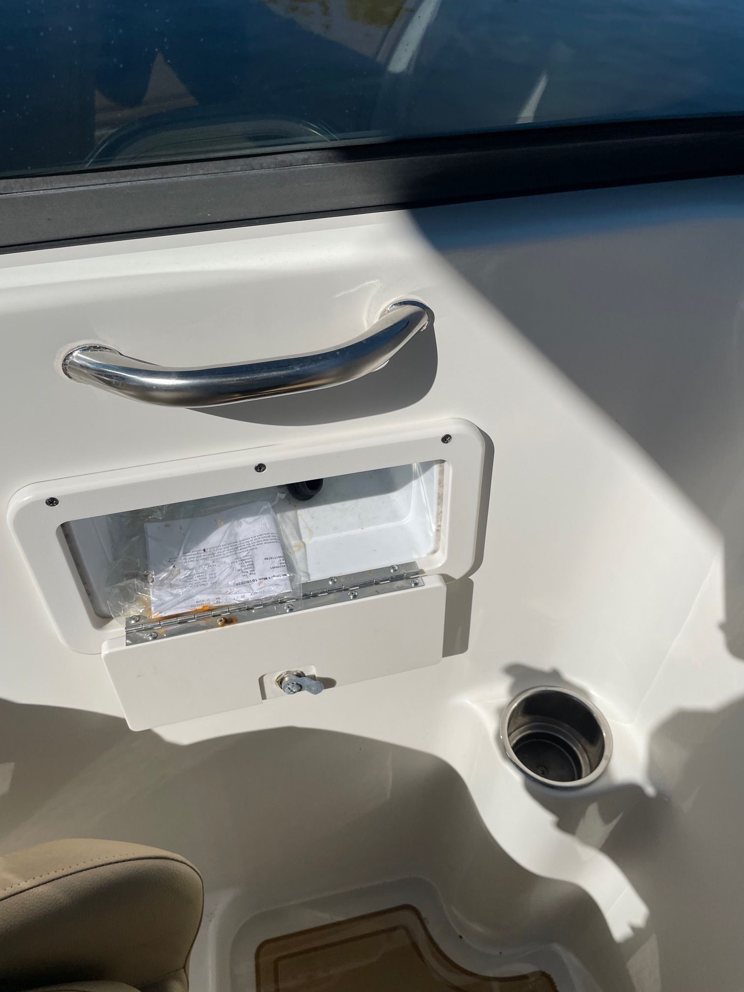 Interior view of a boat with a small storage compartment and a cup holder.