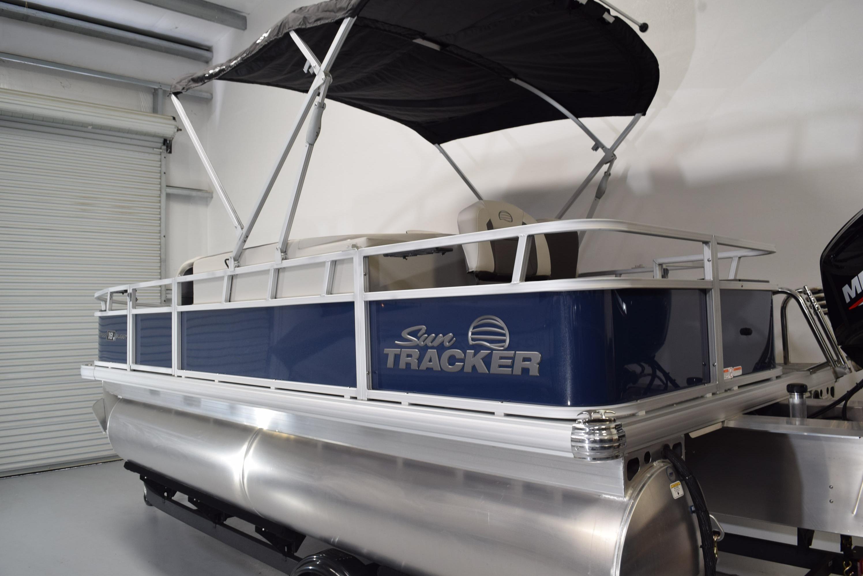 2026 Sun Tracker Bass Buggy 18 DLX pontoon boat with canopy in a showroom.