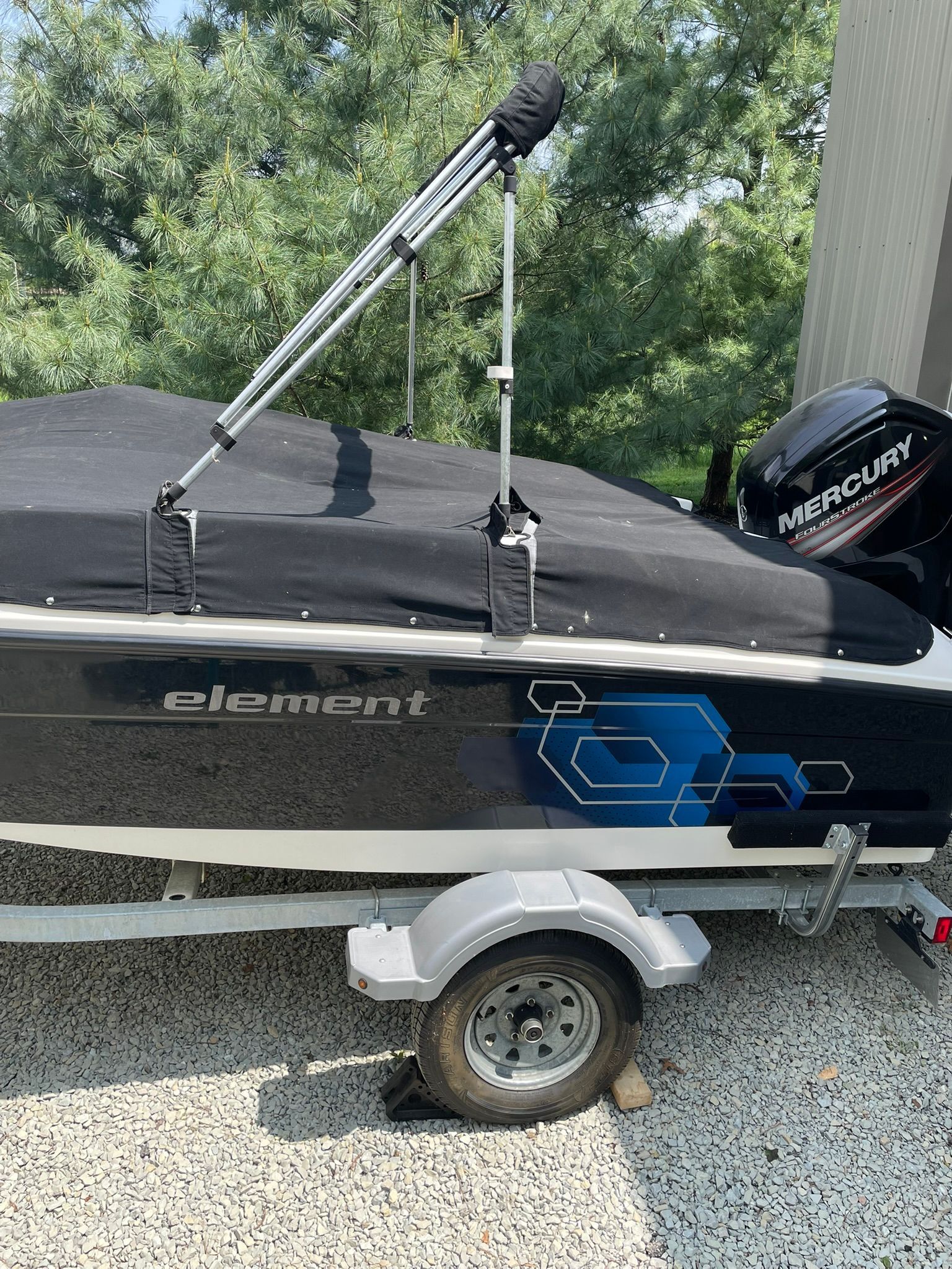 A 2018 Bayliner 160 Bowrider with cover, parked on a trailer.