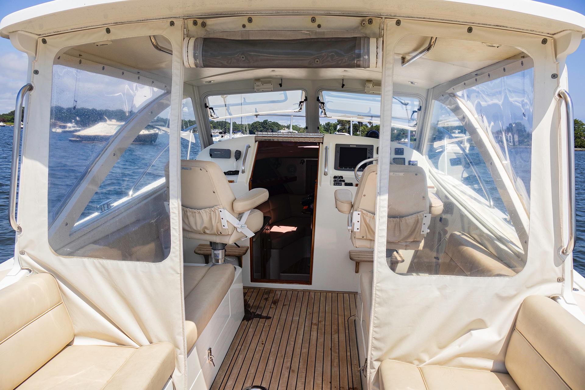 2007 MJM 29z boat interior with helm, seating, and clear enclosures on the water.