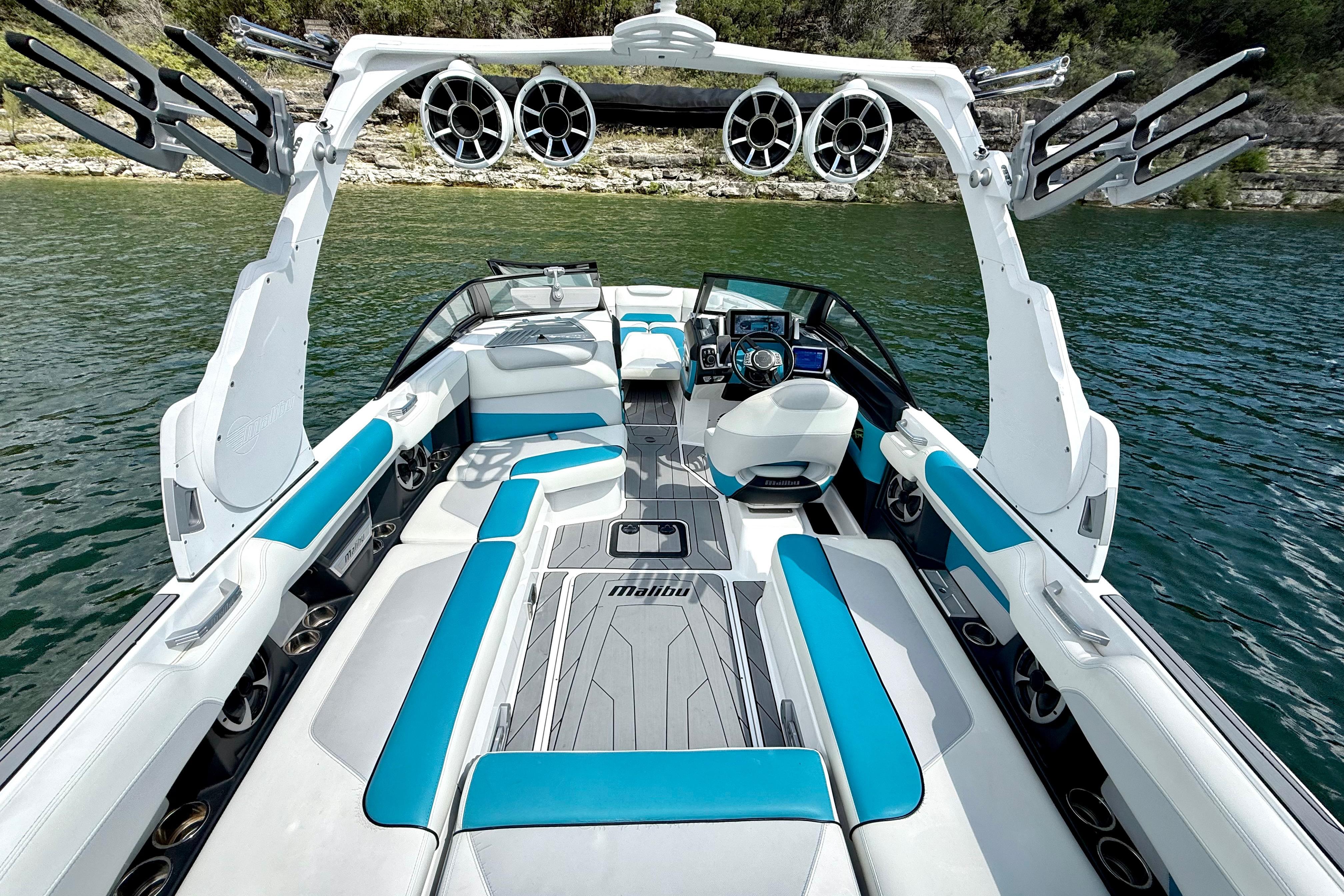 2017 Malibu M235 boat interior with blue and white seating, on a serene lake.