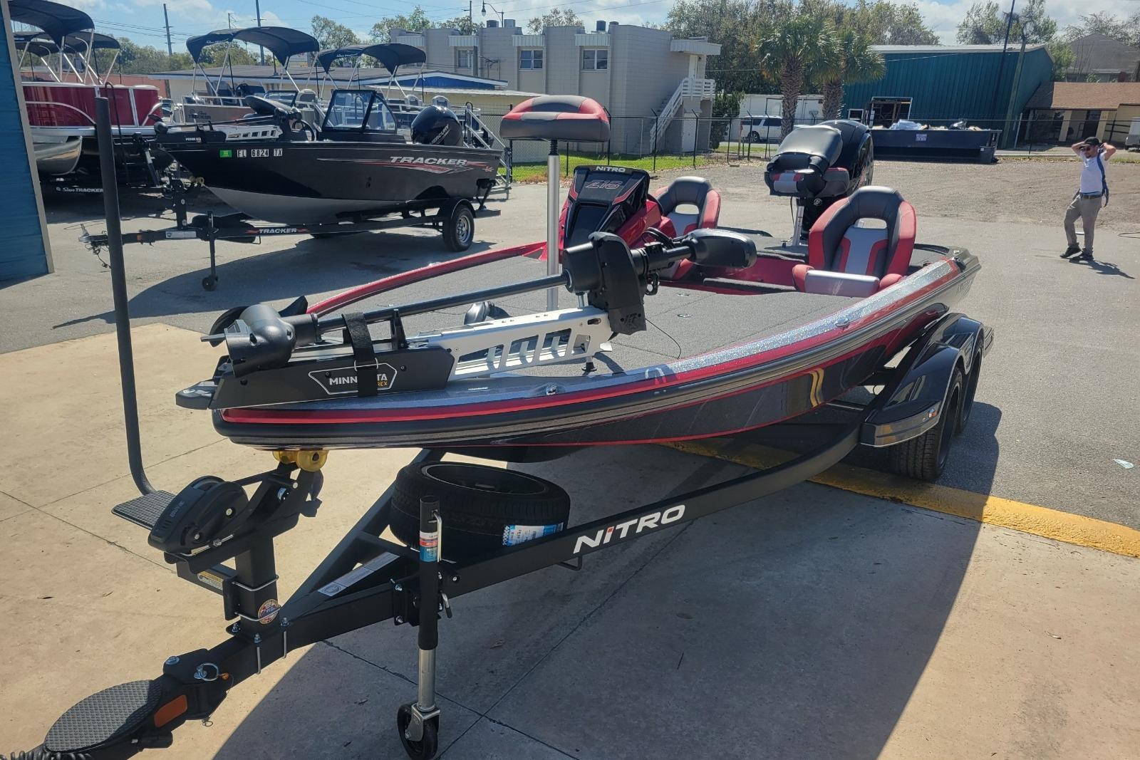 2026 Nitro Z18 boat with trailer, parked outdoors, featuring red and black design.