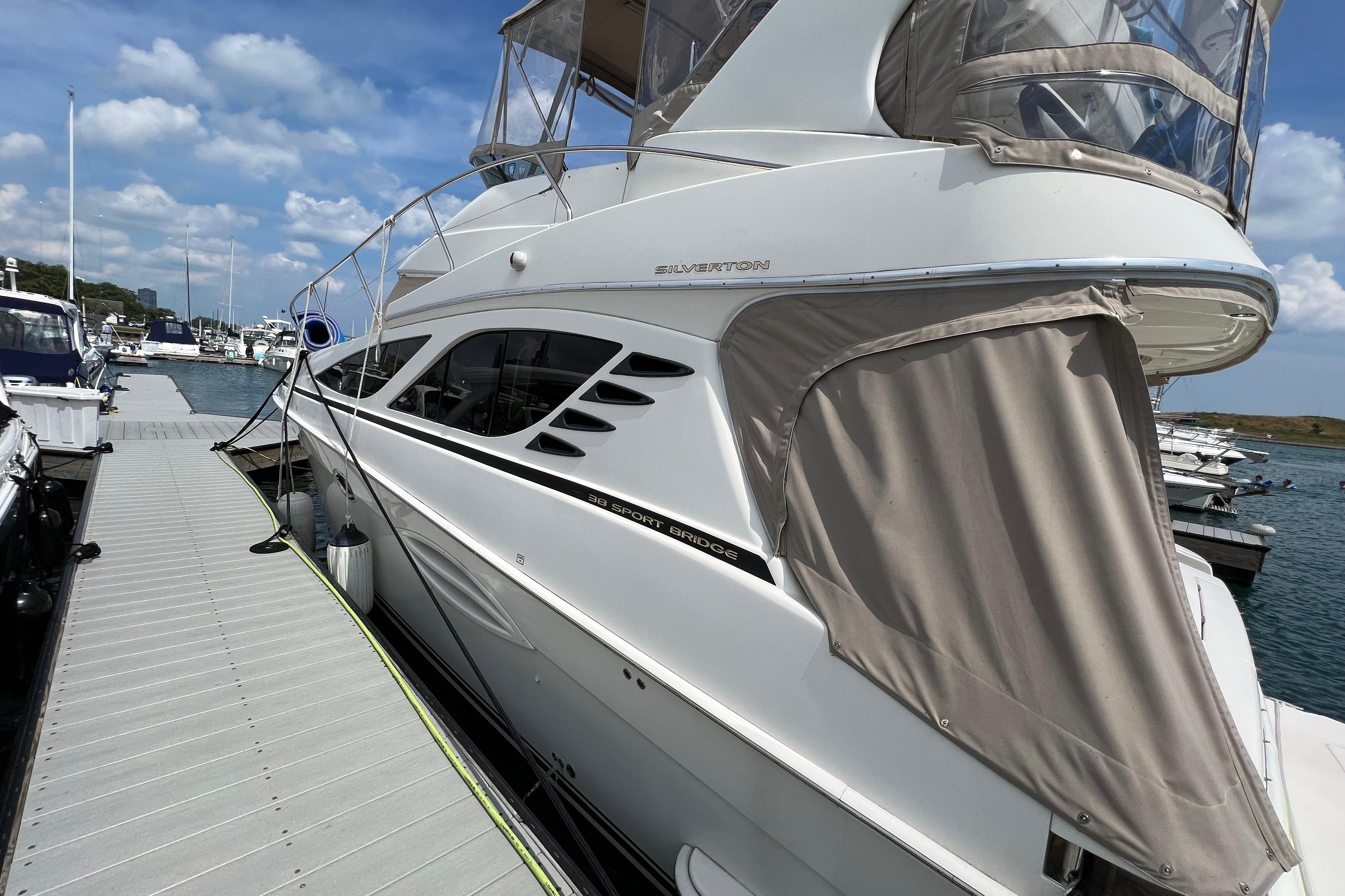 2006 Silverton 38 Sport Bridge yacht docked at marina under blue sky.