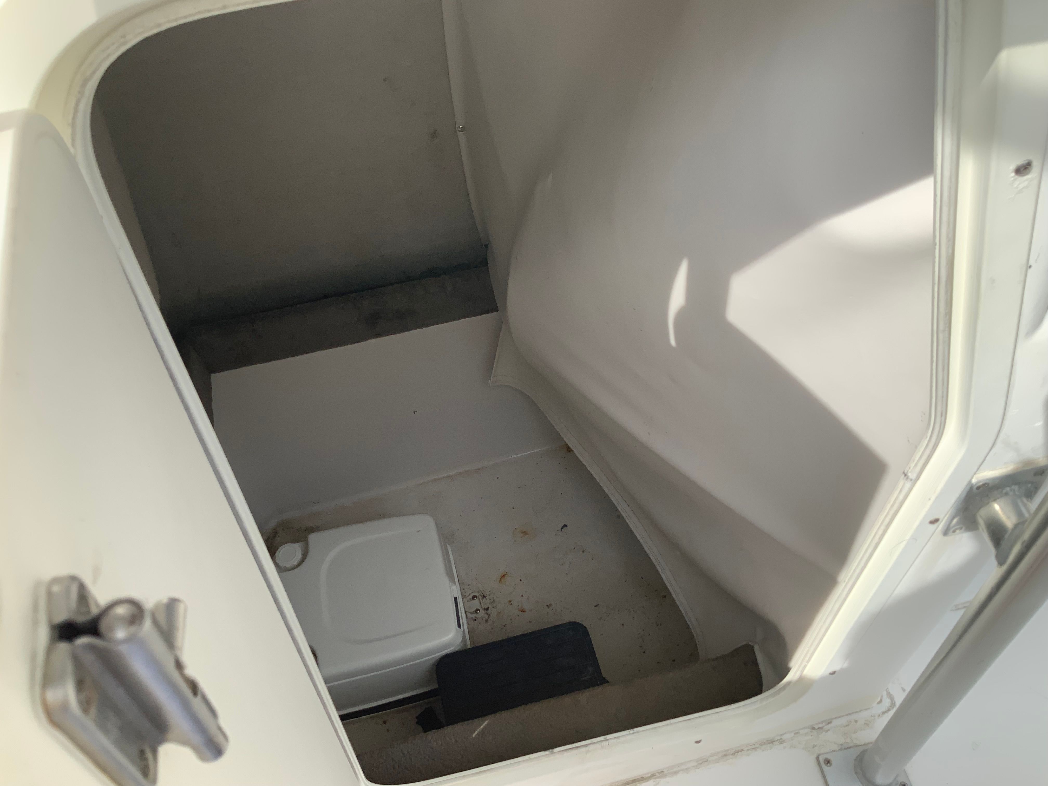 View into a small boat cabin with a portable toilet and basic amenities.