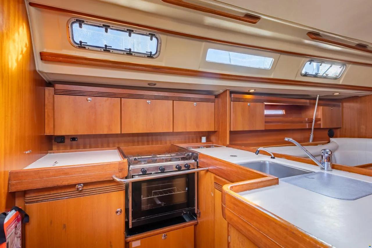 Interior of 2004 Dufour 44 yacht kitchen with wooden cabinetry and modern appliances.