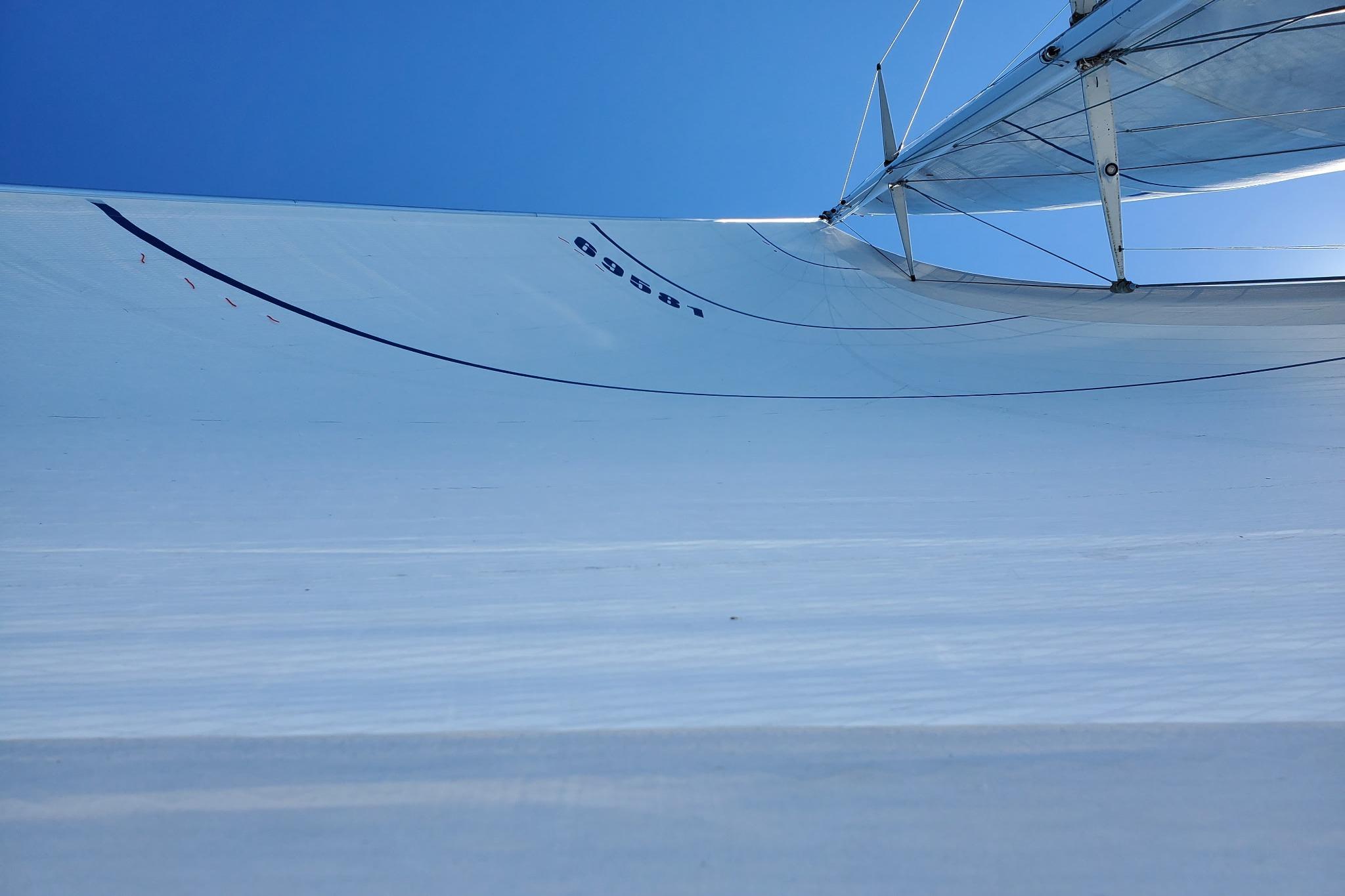 Sail of Abeking & Rasmussen Tripp 74 yacht, 1968, against clear blue sky.