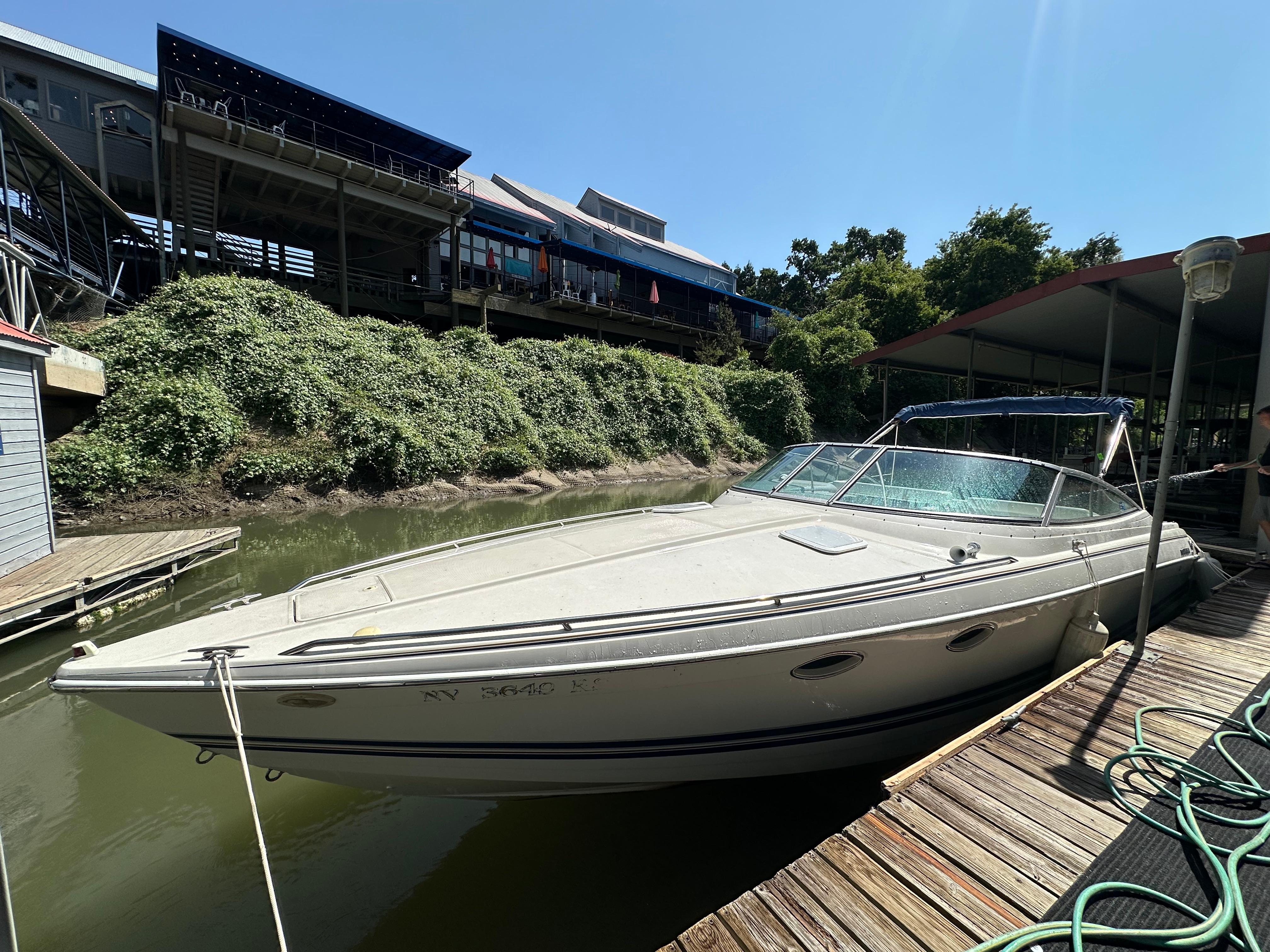 2000 Formula 330 SS boat docked near a wooden pier under sunny skies.