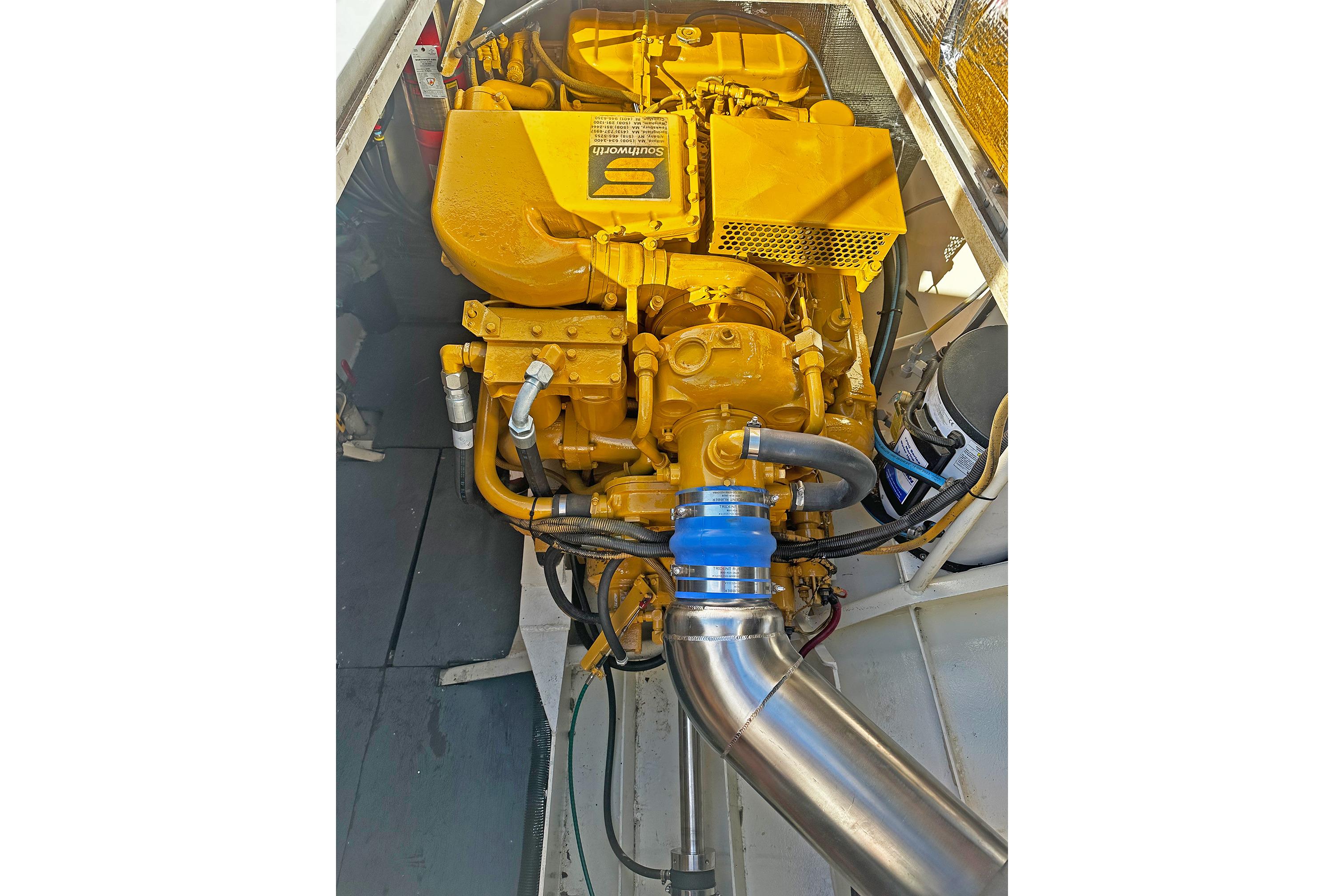 Engine of a 1990 Boston Whaler 36 Defiance, showcasing yellow components and metal piping.