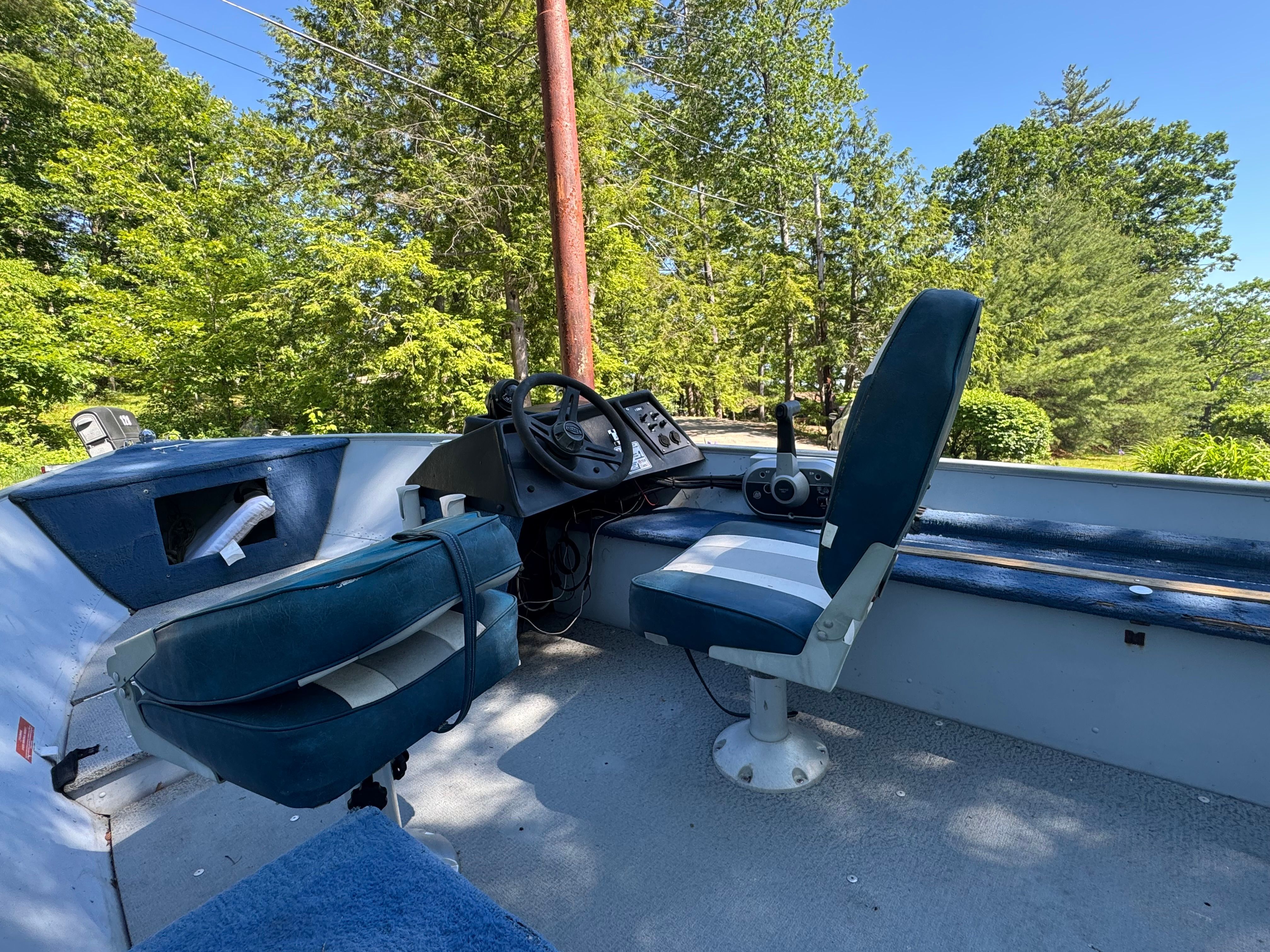 Interior view of a boat with two seats and a steering console.