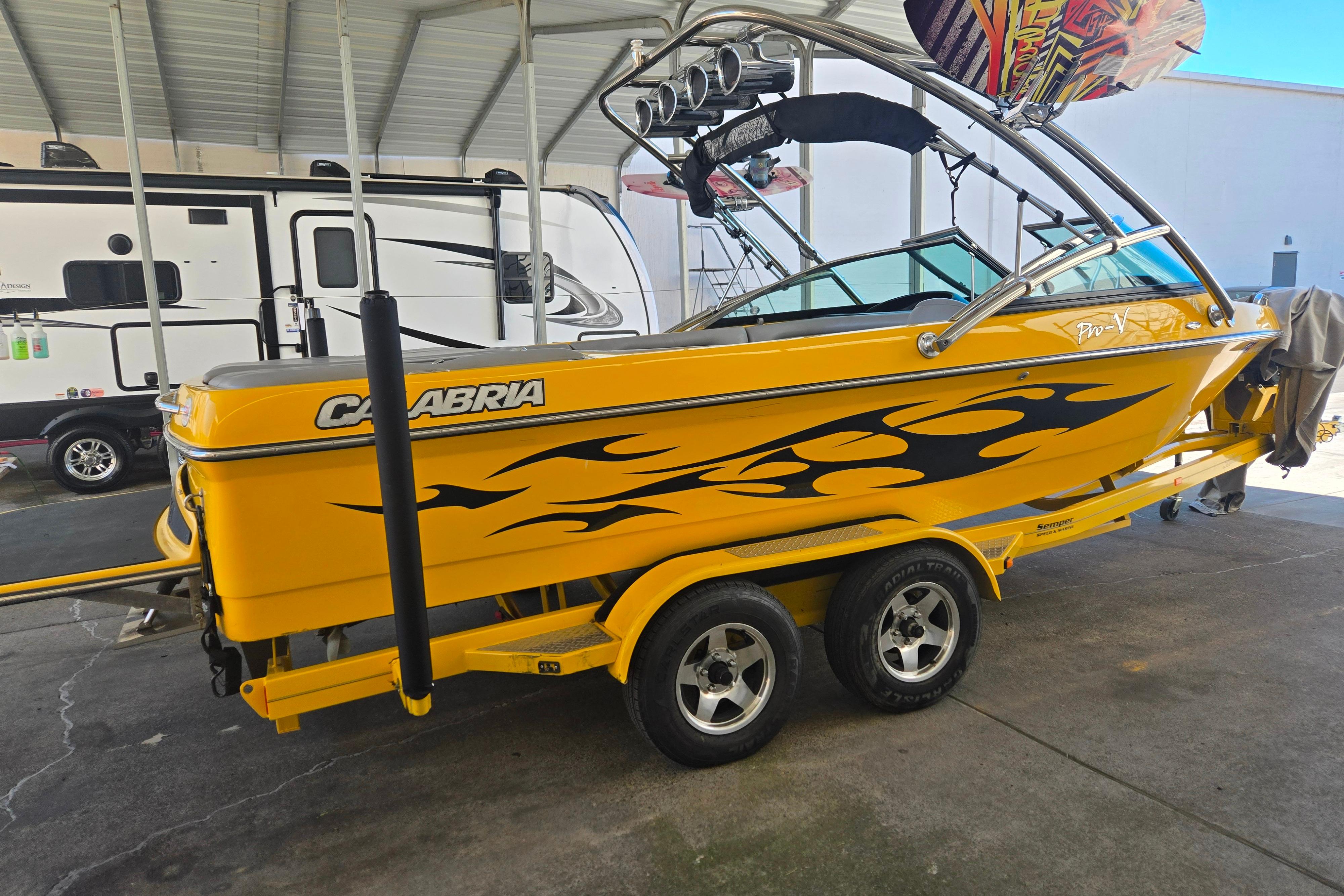 Yellow 2007 Calabria CAL AIR PRO V boat with flame decals on a trailer.