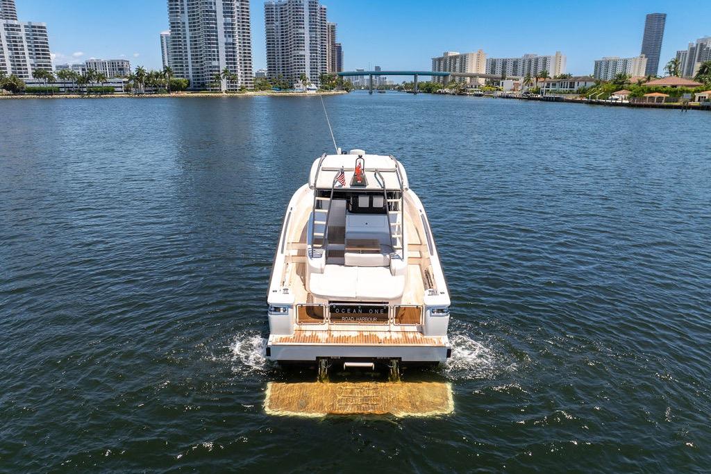 2021 Bluegame BG 42 yacht cruising in urban waterfront setting with skyscrapers.