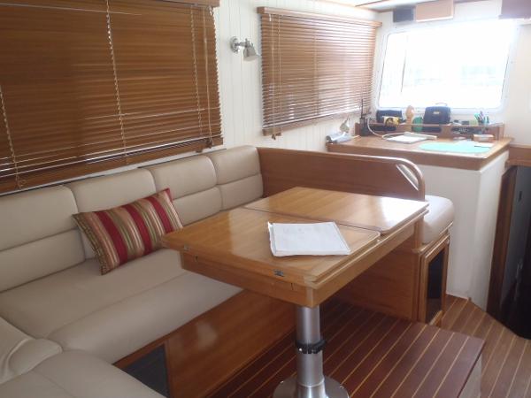 Interior of 2025 Great Harbour N40 yacht with beige seating and wooden table.