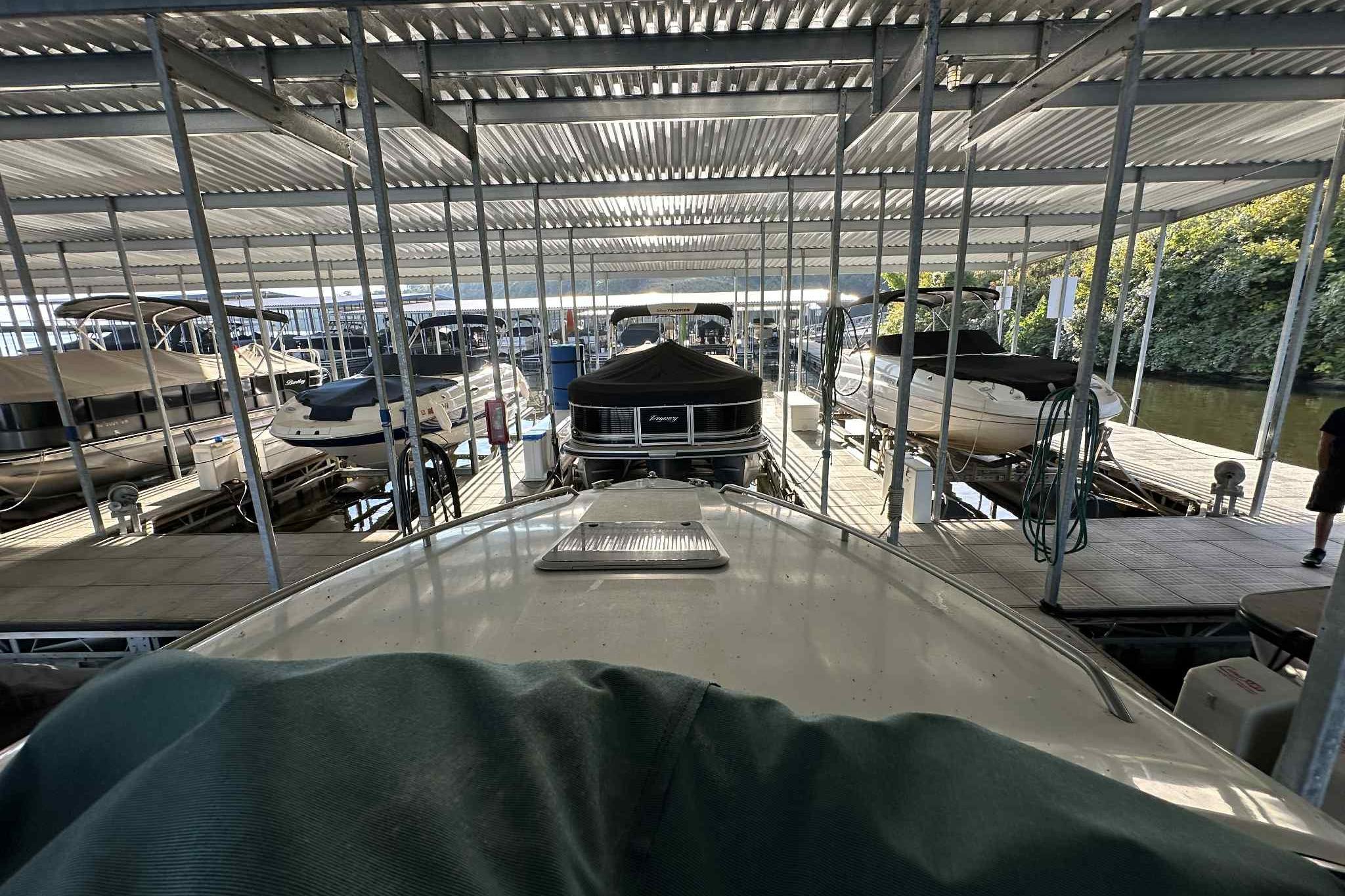 Covered marina with various boats, including a 1995 Genesis Boats 2505, docked in slips.