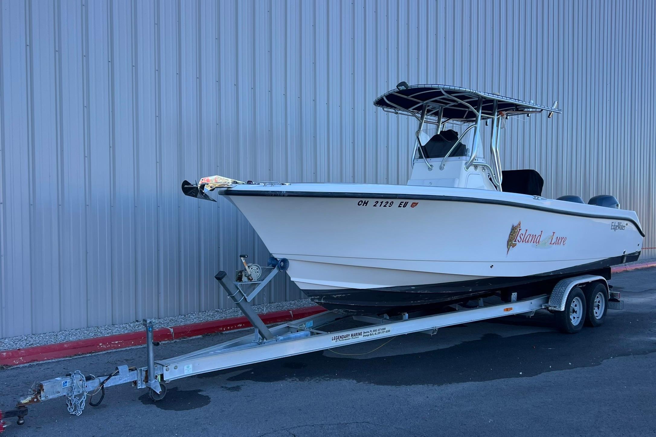 2006 Edgewater 245CC boat on trailer, parked beside a metal building.