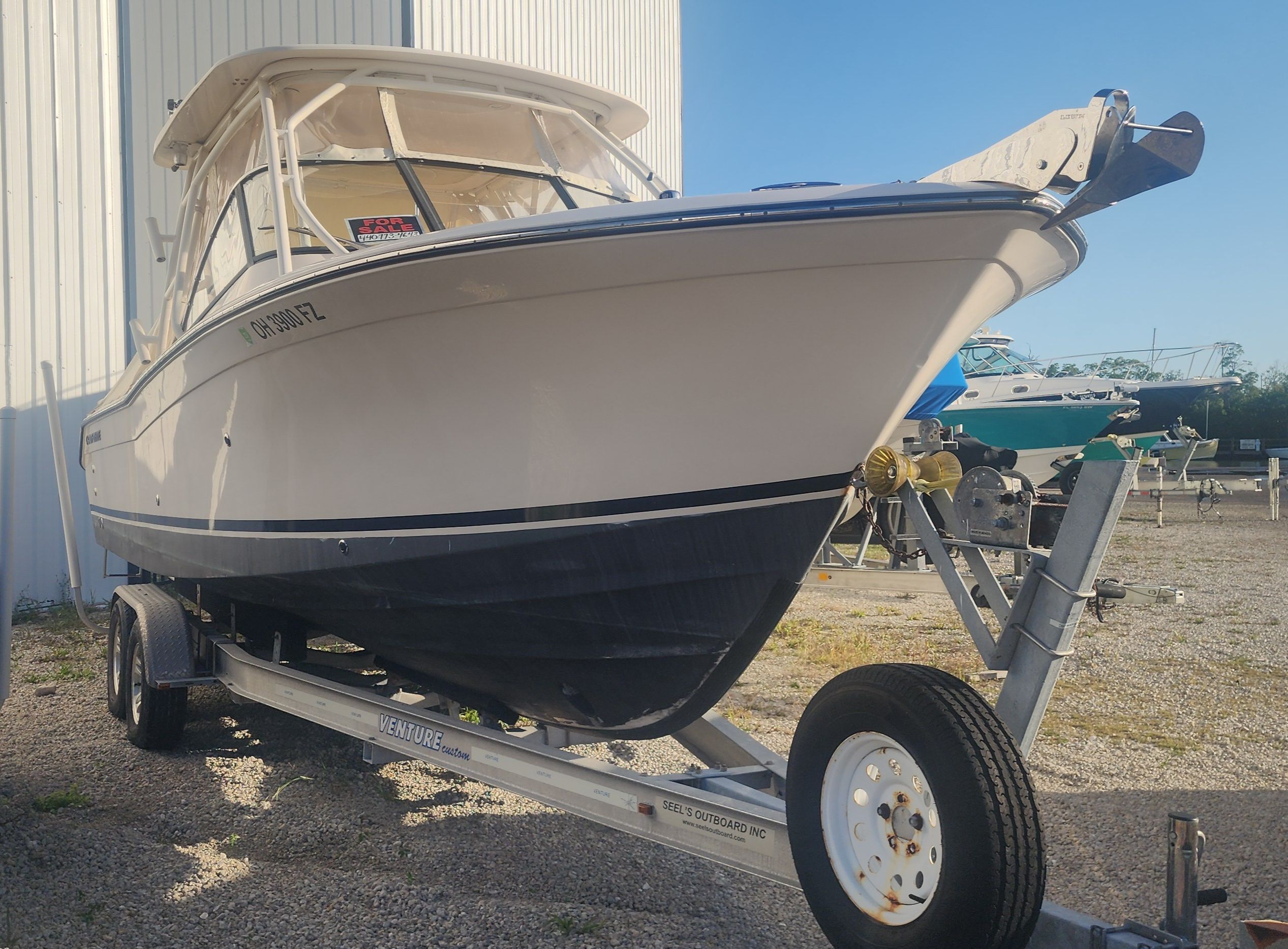 A 2015 Grady-White Freedom 275 boat on a trailer beside a building.