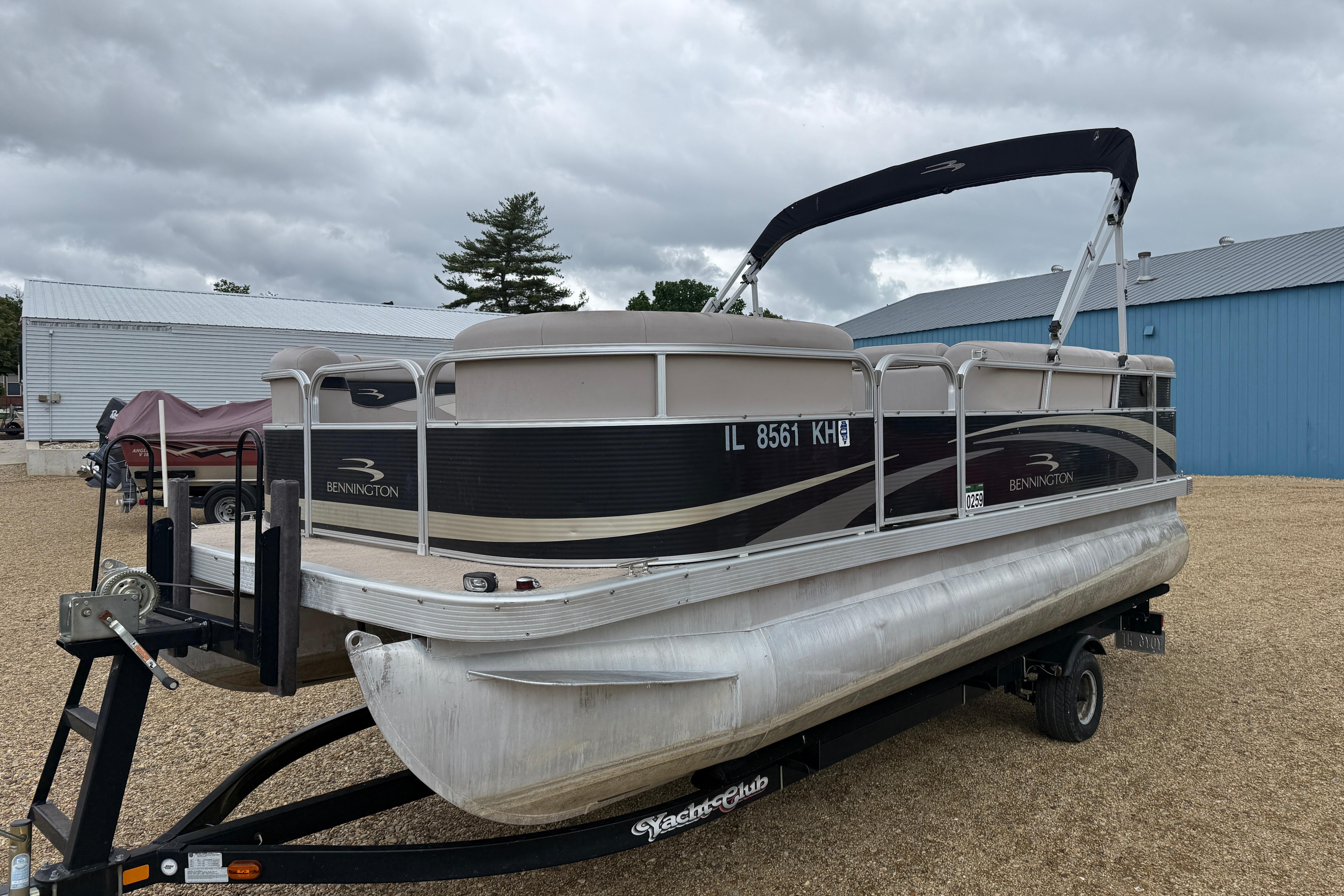 2010 Bennington 20SLi pontoon boat on trailer, parked outdoors under cloudy sky.