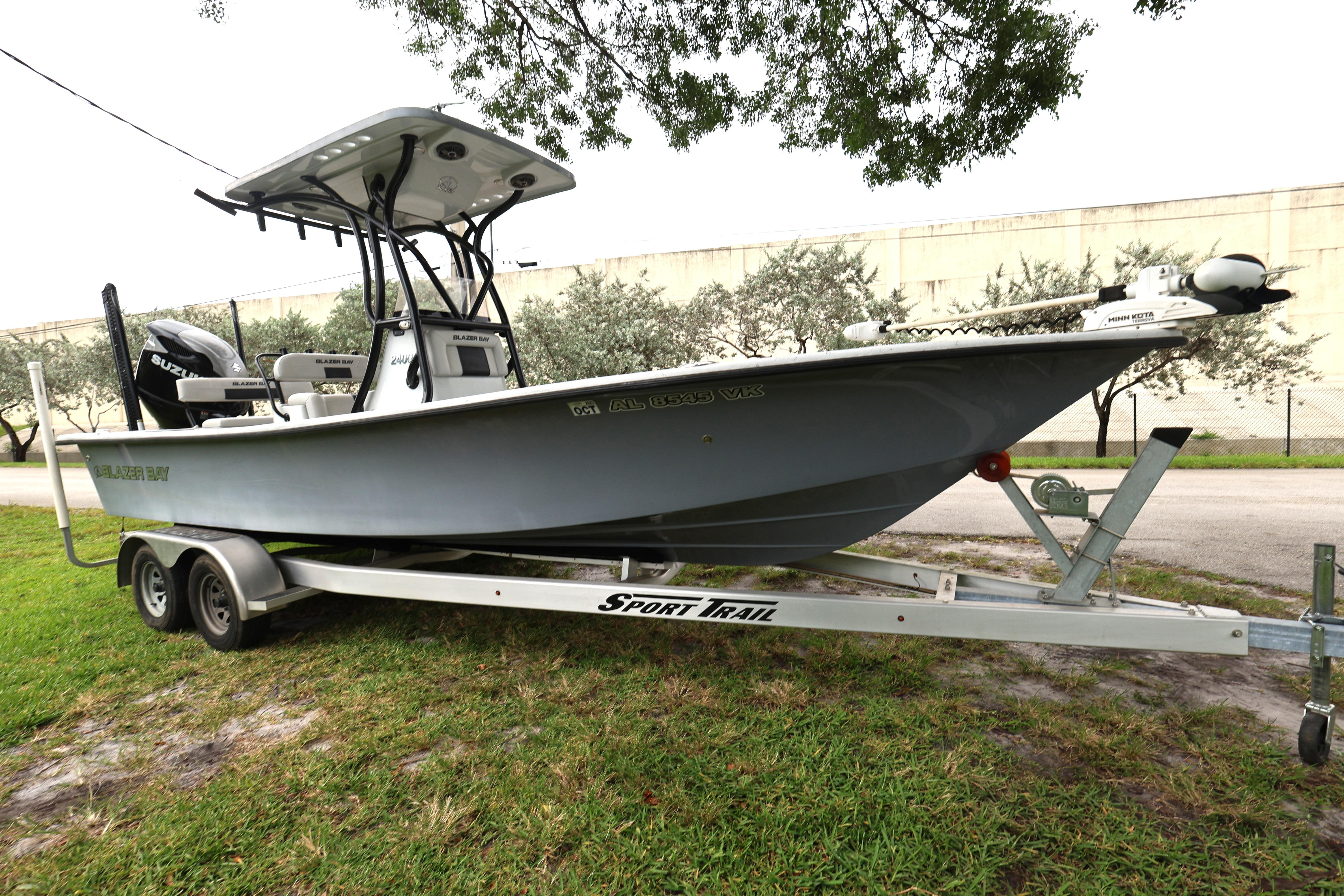 2021 Blazer Bay 2400 boat on trailer, parked on grass, side view.