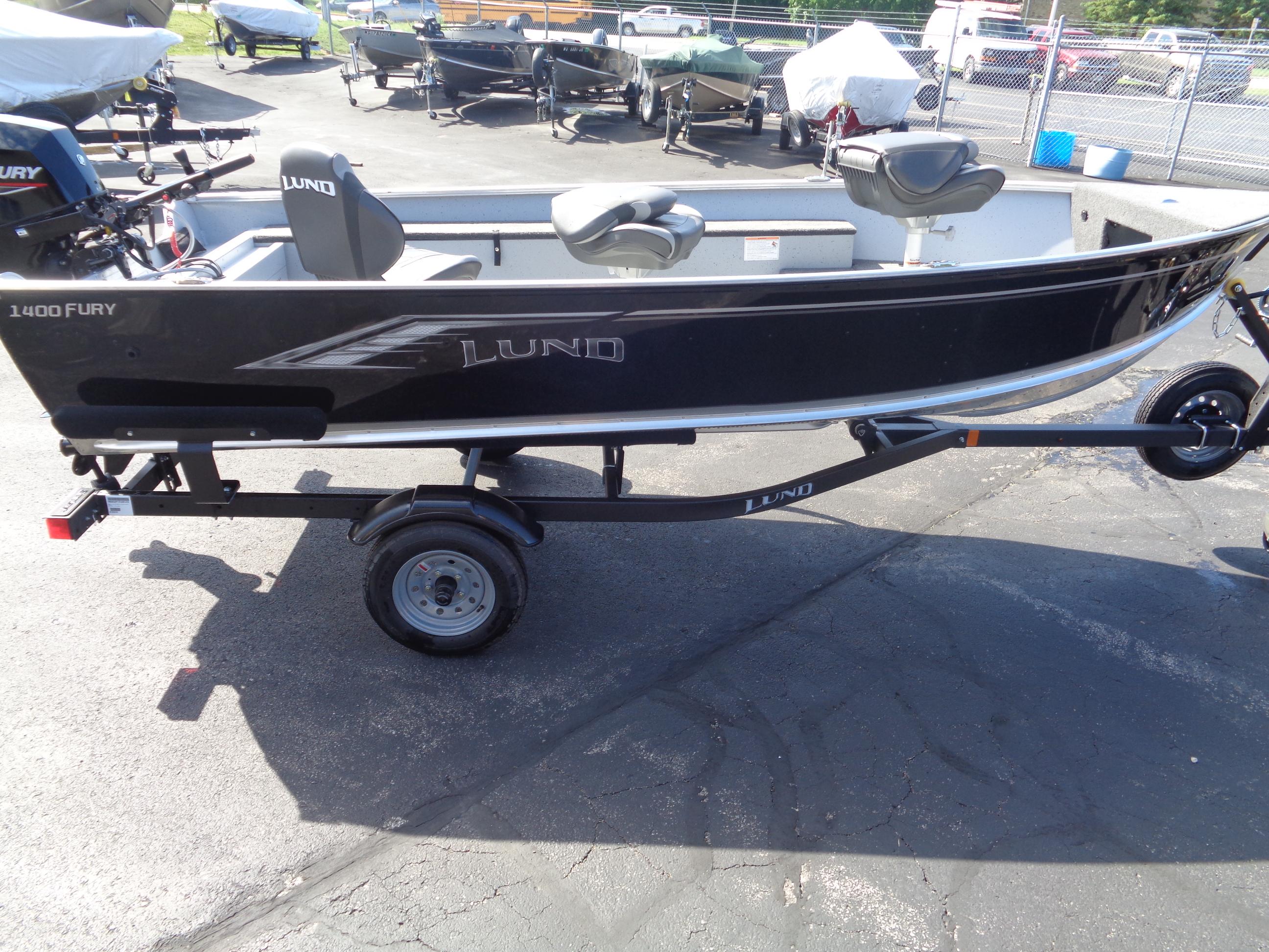 2025 Lund 1400 Fury Tiller boat on trailer, parked outdoors.