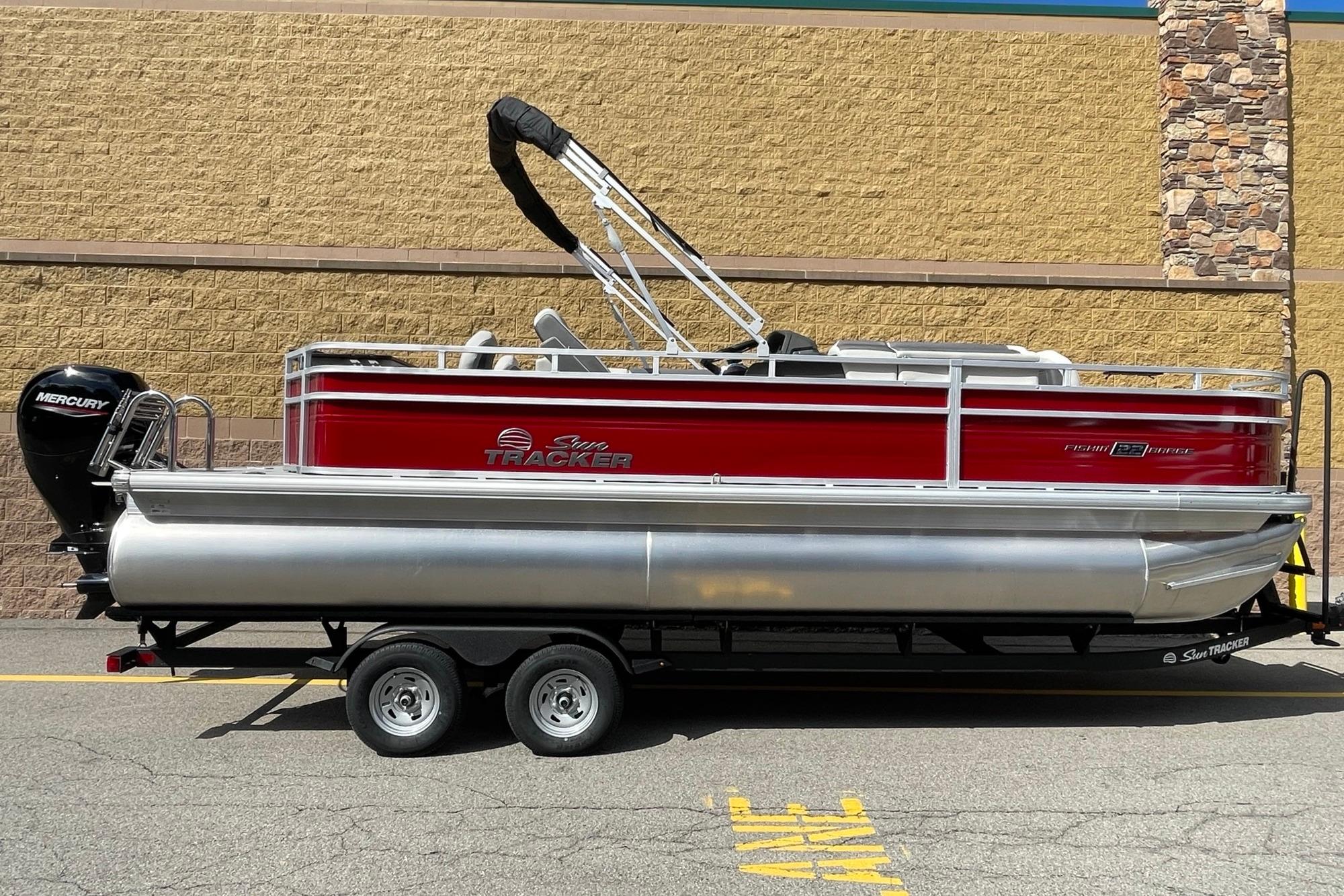 2026 Sun Tracker Fishin' Barge 22 DLX pontoon boat on trailer, side view.