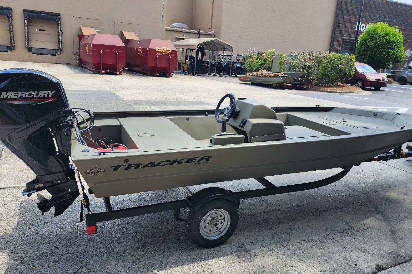2026 Tracker Grizzly 1648 SC boat with Mercury engine on trailer in parking lot.