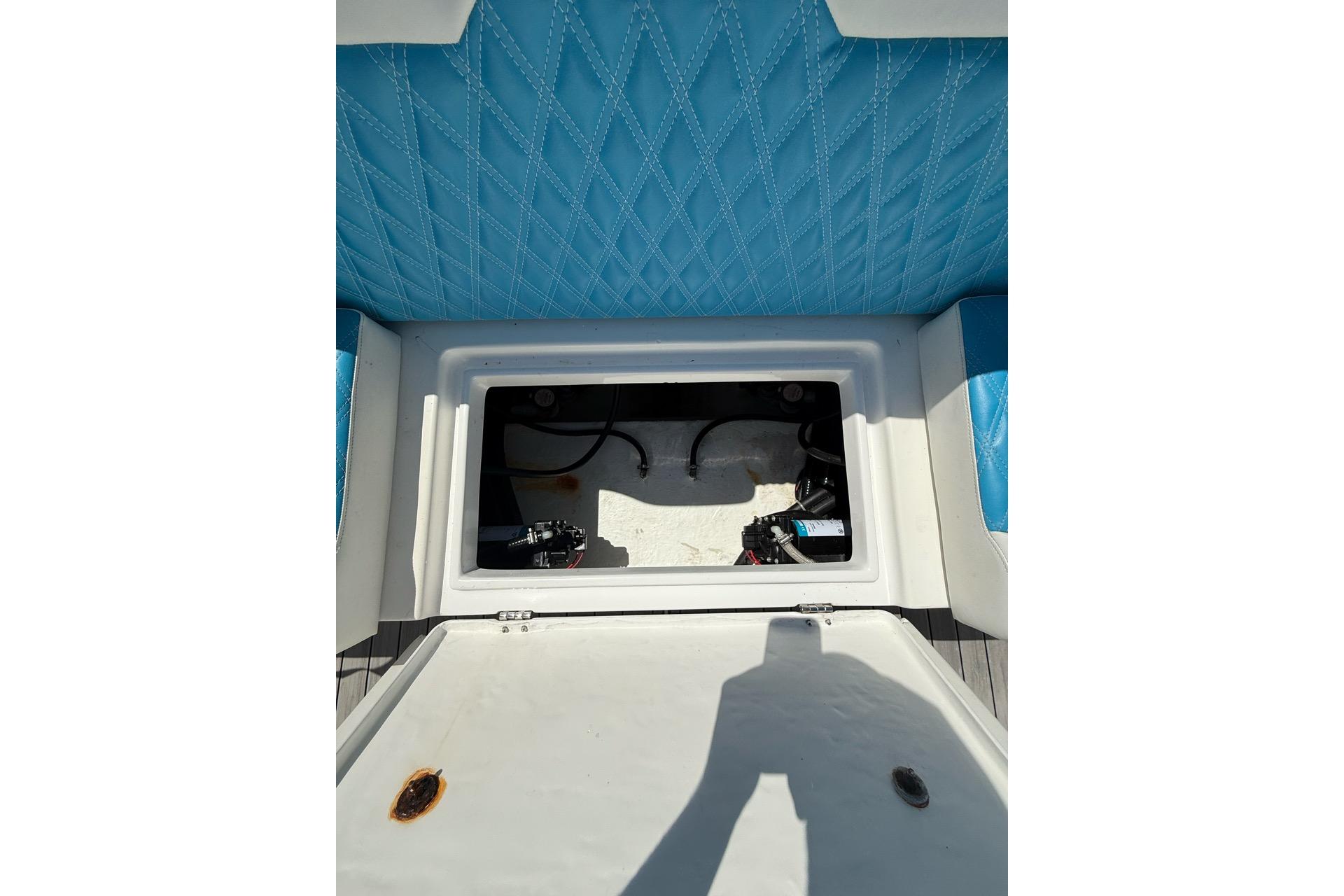 Open storage compartment on 2021 Custom Infusion 34 CC boat with blue quilted seating.