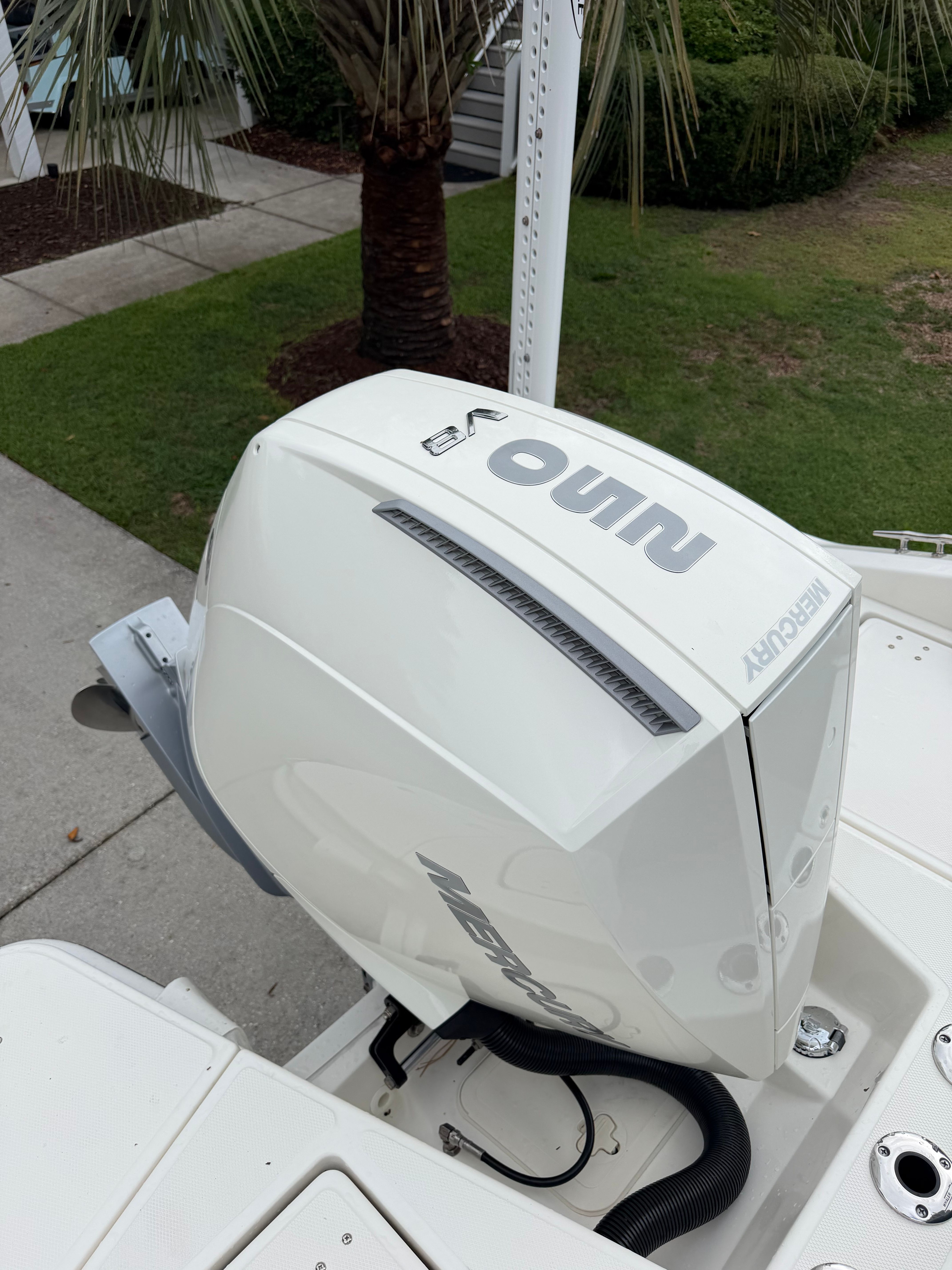 An outboard motor on a boat, surrounded by a well-kept garden with palm trees.
