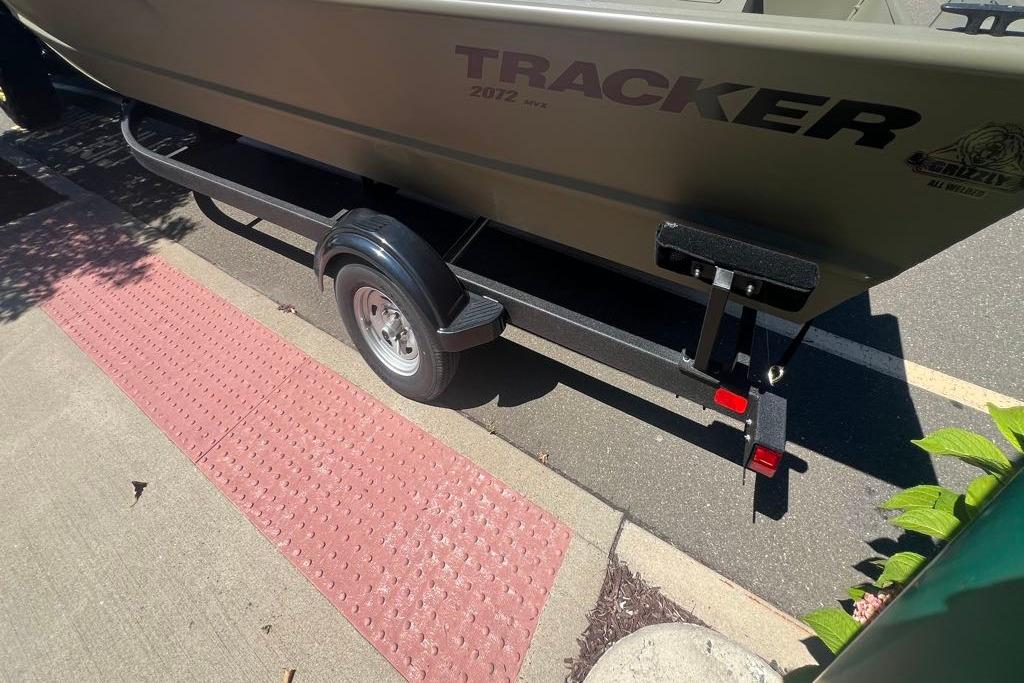 2026 Tracker GRIZZLY 2072 Utility boat on trailer, parked on a street.