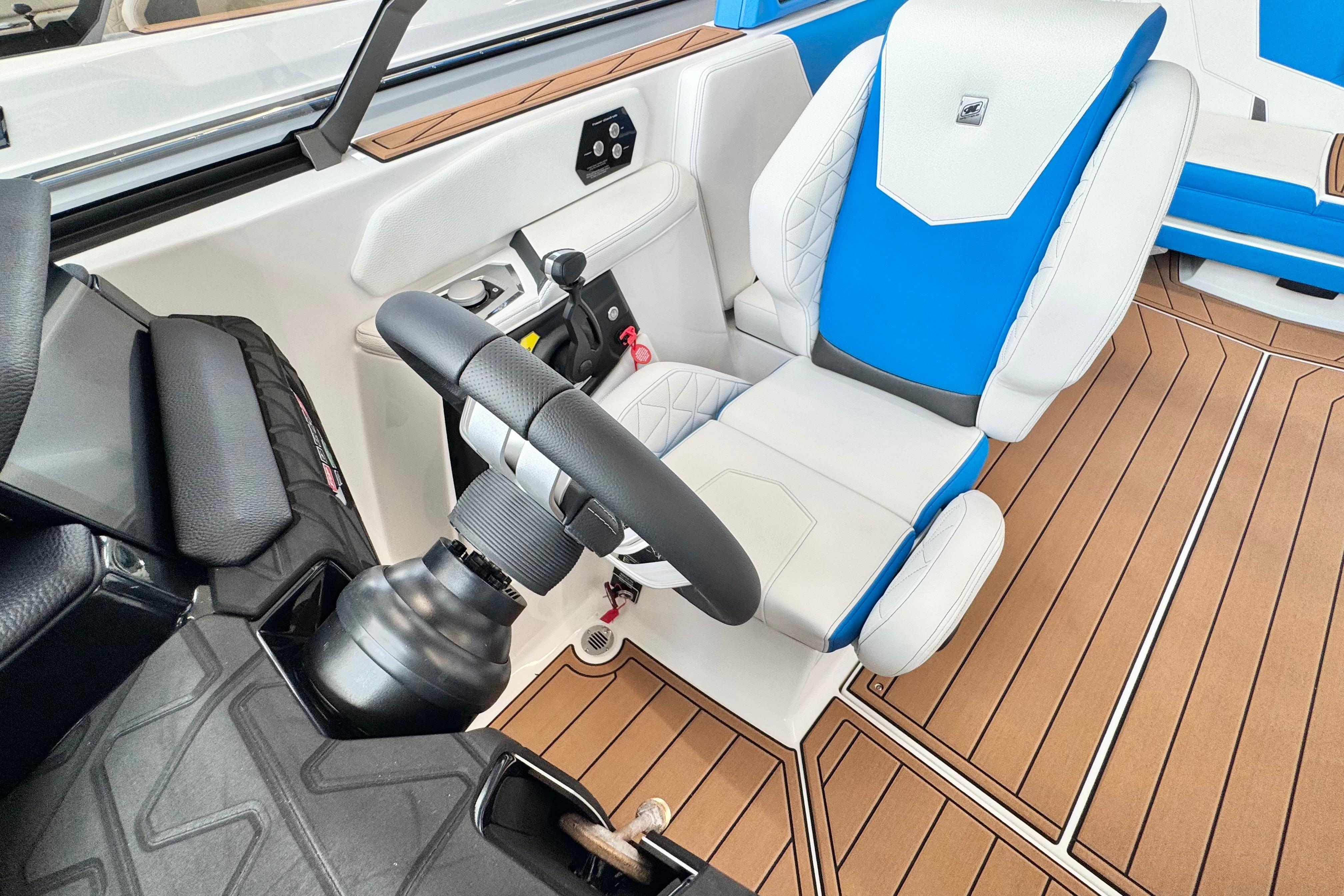 2026 Nautique Super Air Nautique GS22 cockpit with blue and white seating, modern controls, and wood flooring.