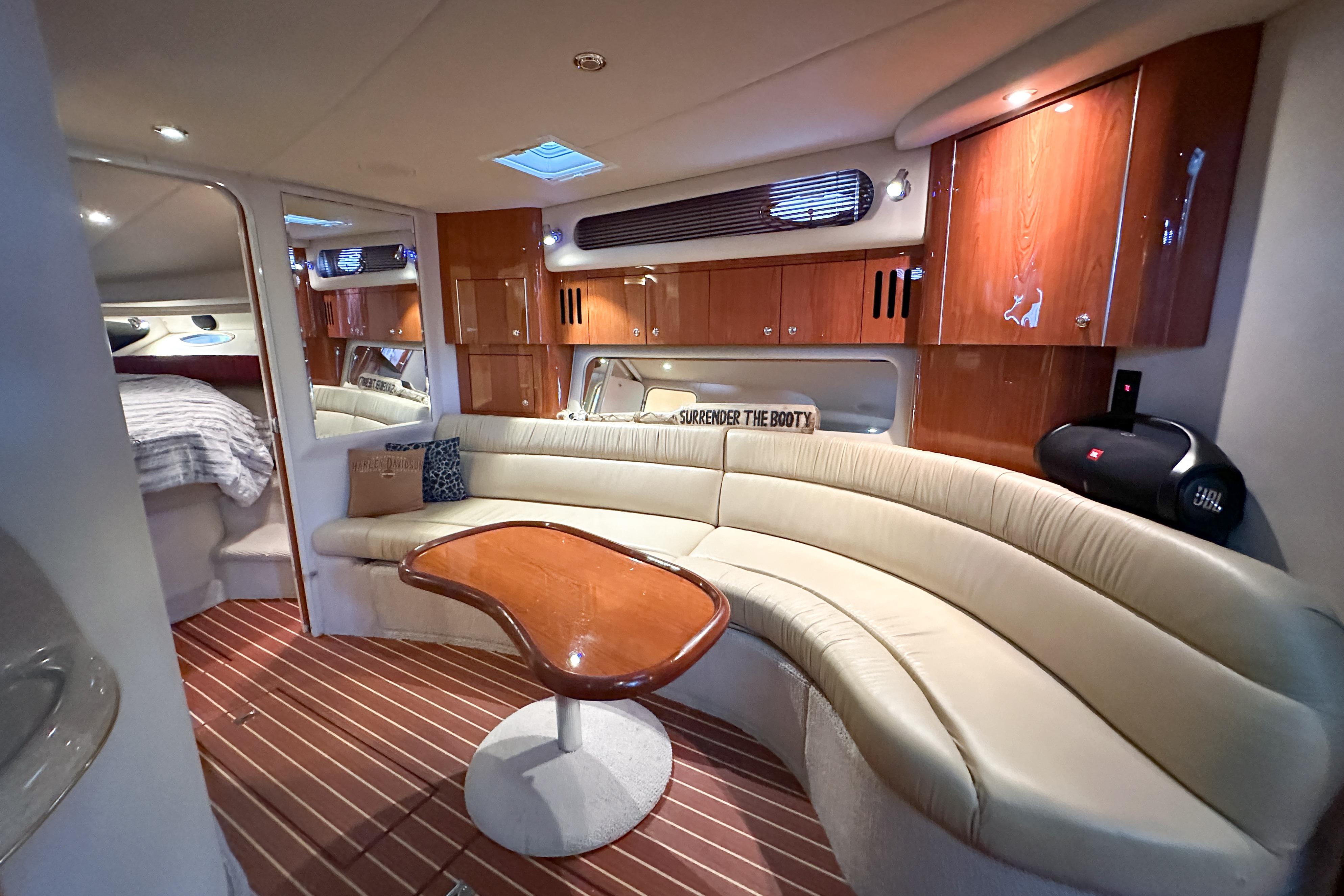 Luxurious interior of 2001 Sea Ray 410 Sundancer yacht with curved seating and wooden cabinetry.