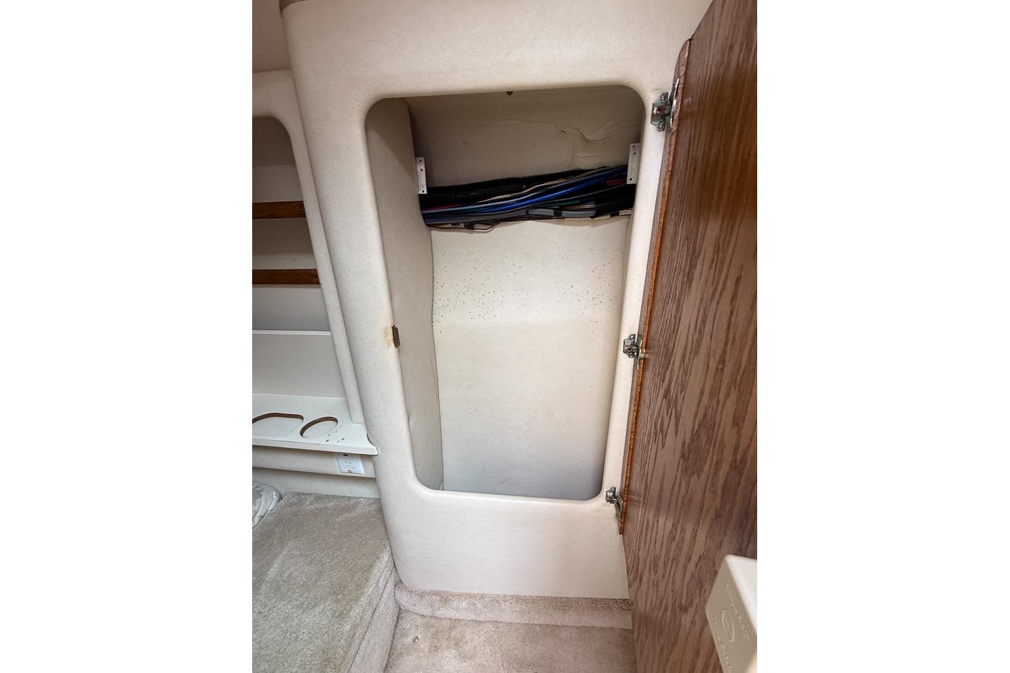 1999 Sea Ray 290 Sundancer interior storage compartment with open wooden door.