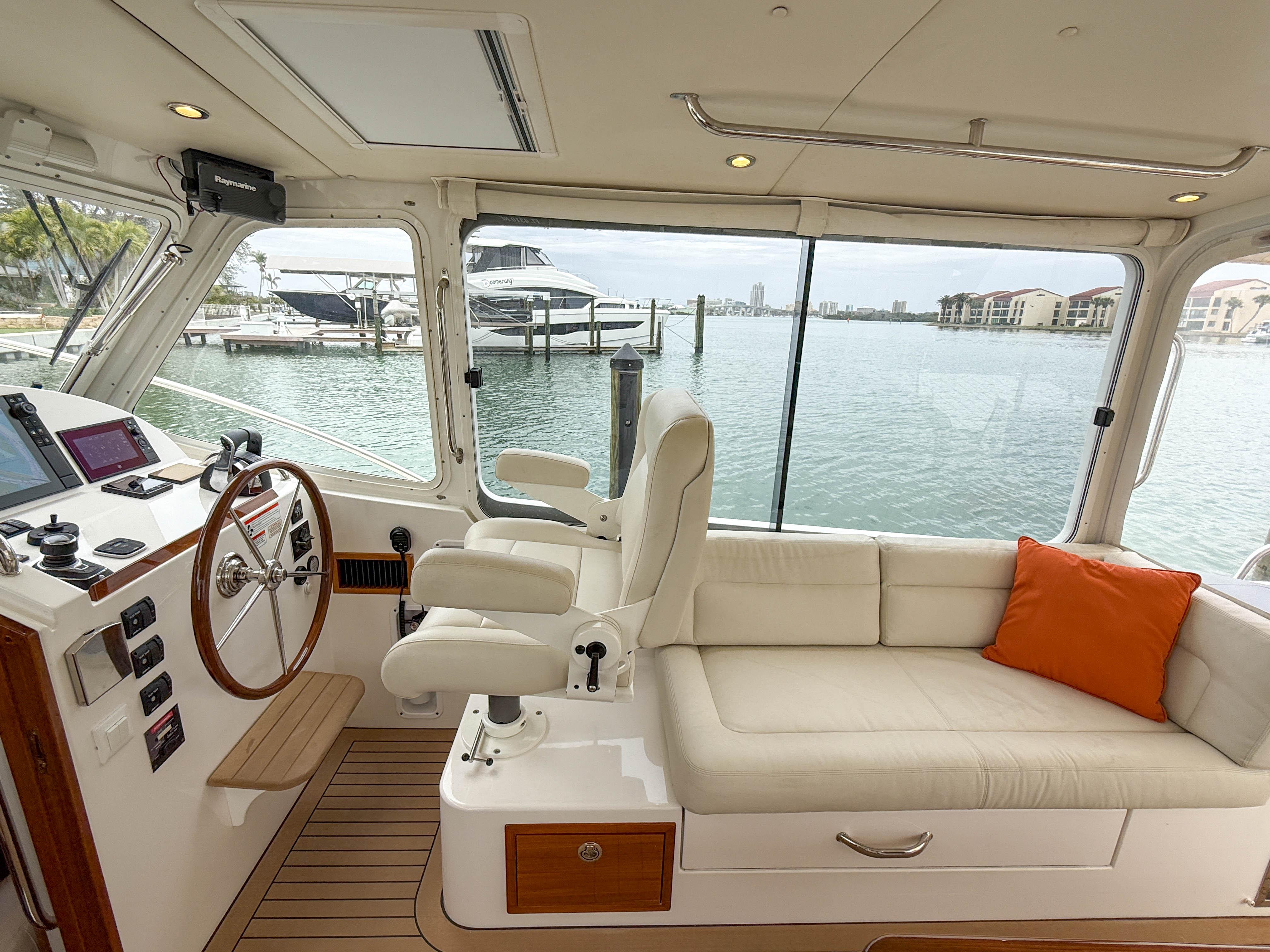 Interior of 2019 MJM 43z yacht with helm, seating, and waterfront view.