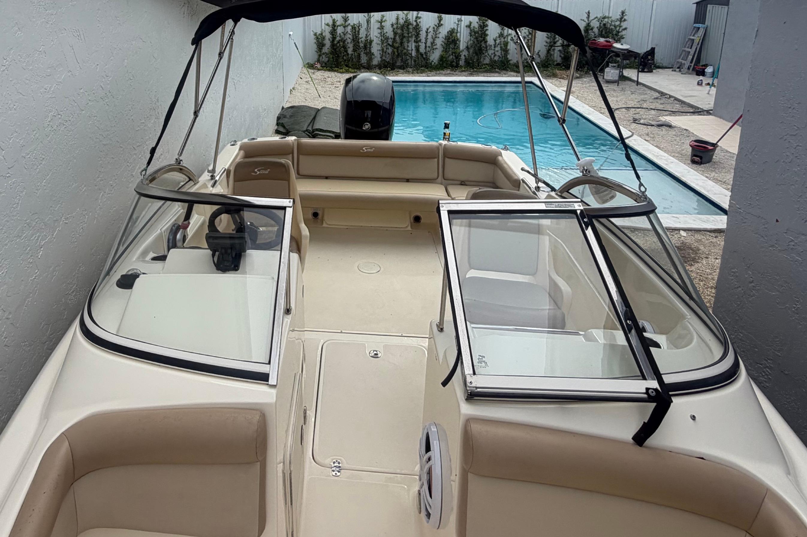 2023 Scout 210 Dorado boat with open cockpit, near a swimming pool.