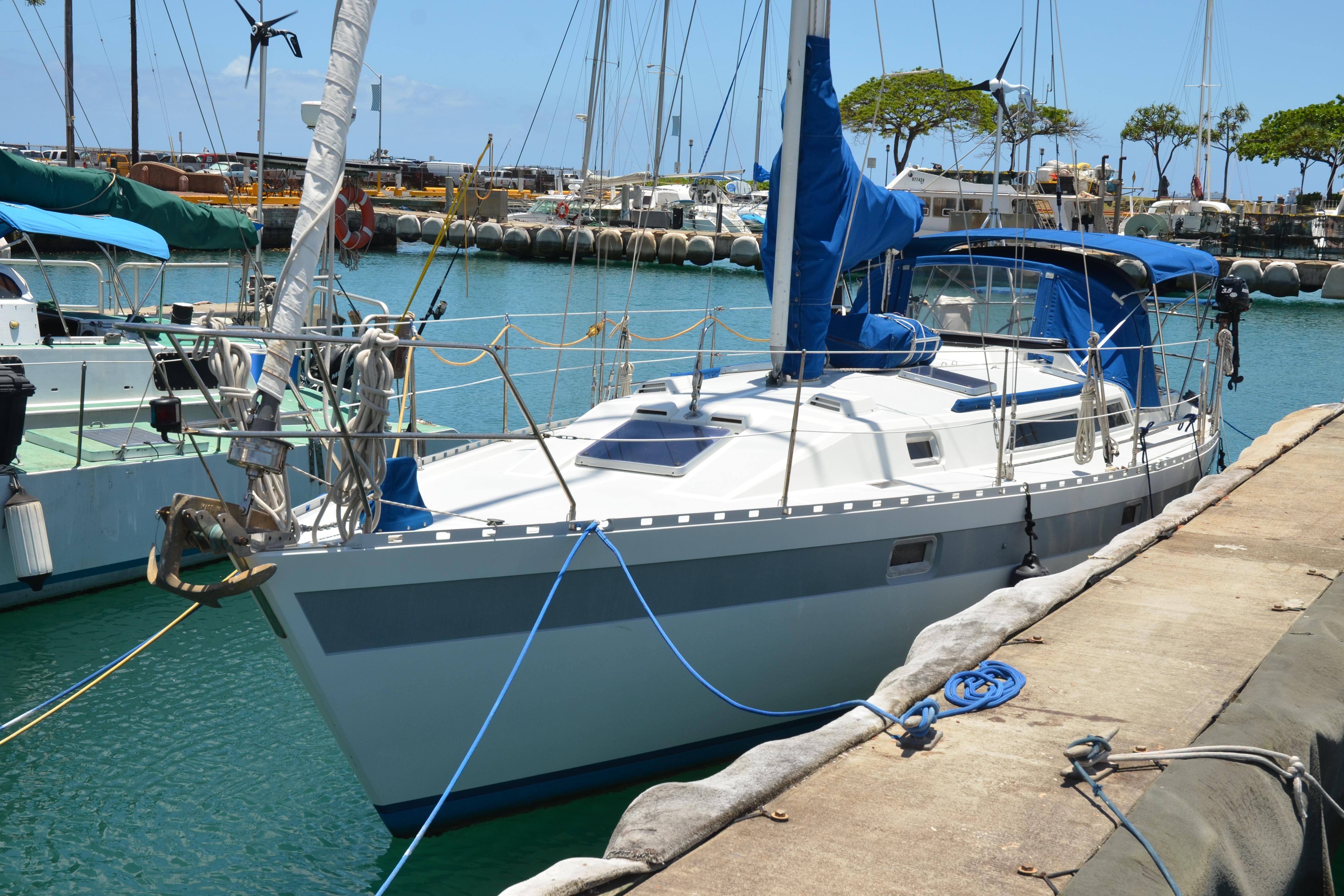 1987 Norseman 400 sailboat docked in a marina, featuring blue accents and clear skies.