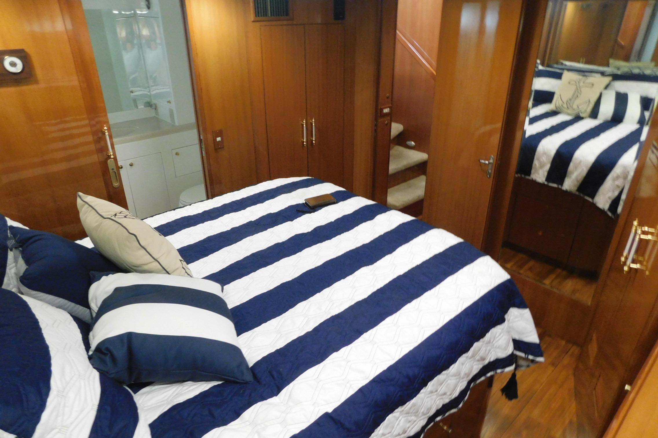 Luxurious bedroom interior of 2001 Jefferson Pilothouse 57 yacht with striped bedding.