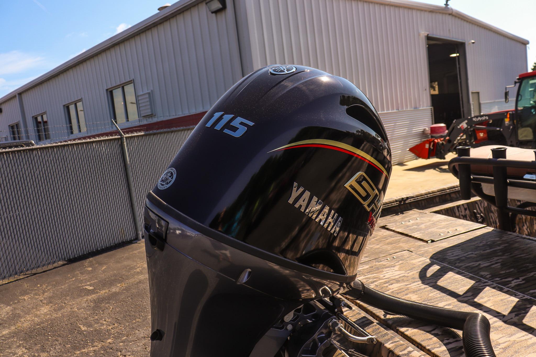 Yamaha 115 HP outboard motor on a boat, with an industrial building in the background.