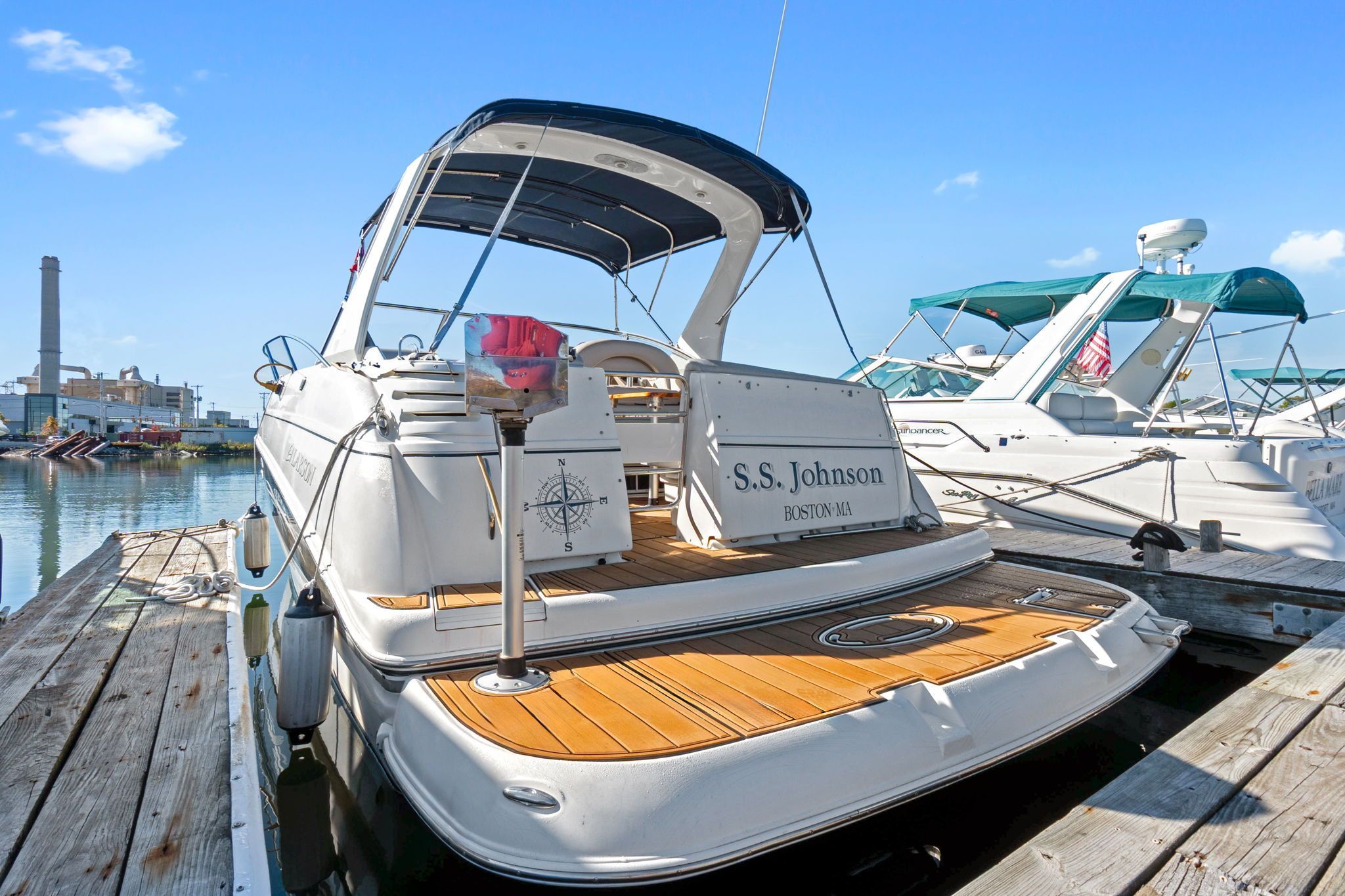 A 2007 Larson Cabrio 330 docked. It features an open cockpit and a blue canopy.
