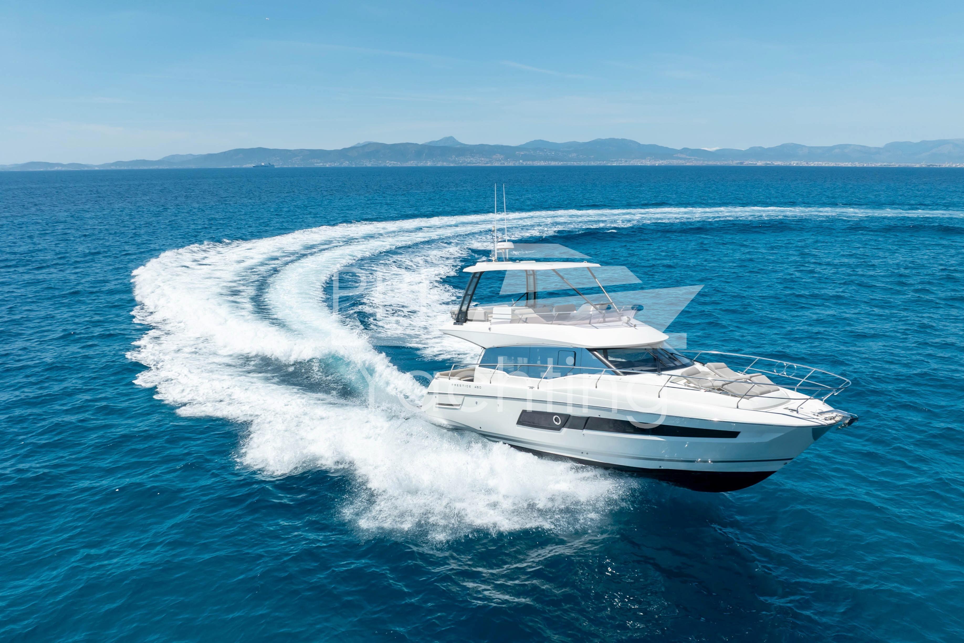 Luxury 2019 Prestige 460 yacht cruising on open sea with scenic coastline backdrop.