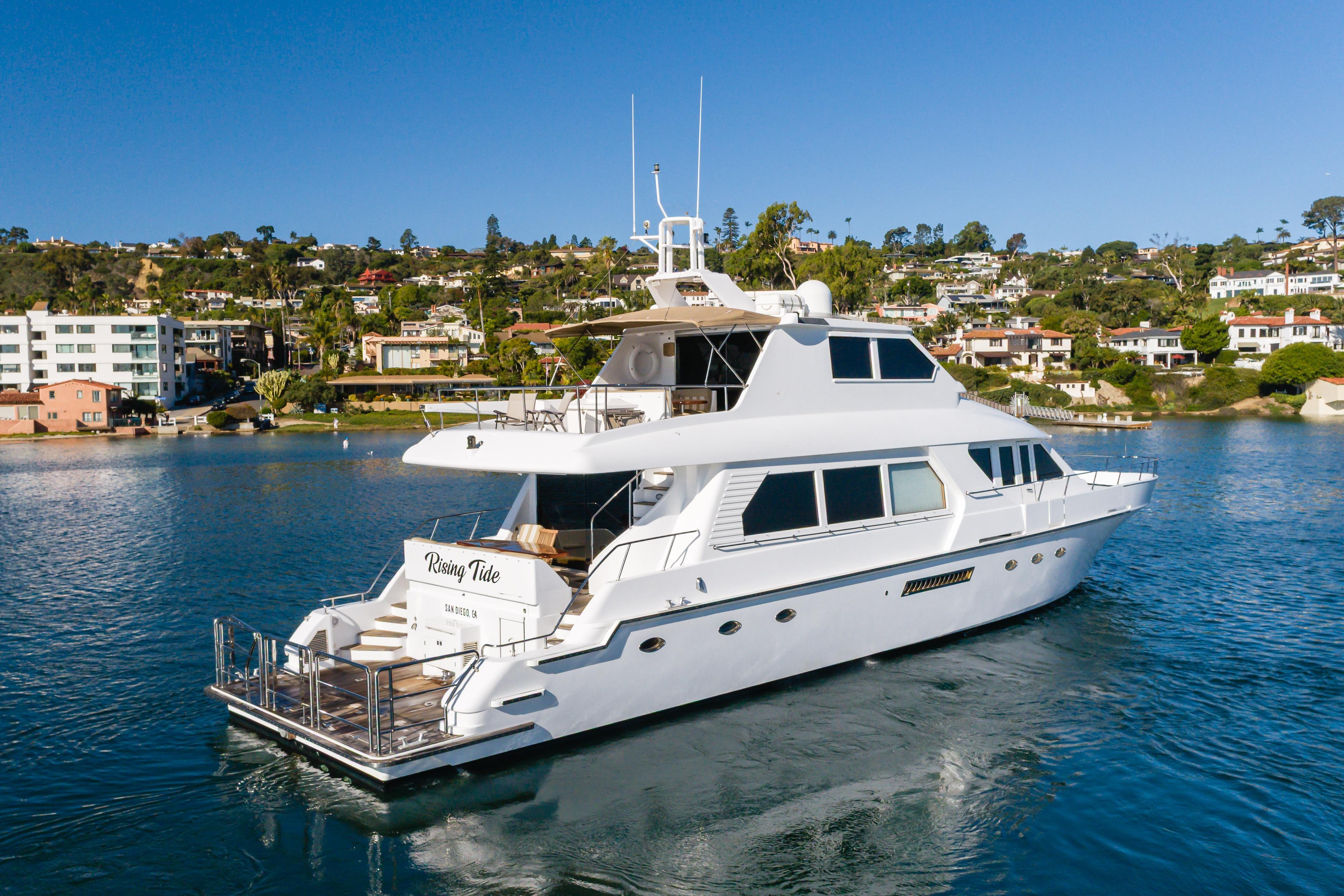 1997 Forbes Cooper Pilothouse yacht on serene water with coastal homes in the background.