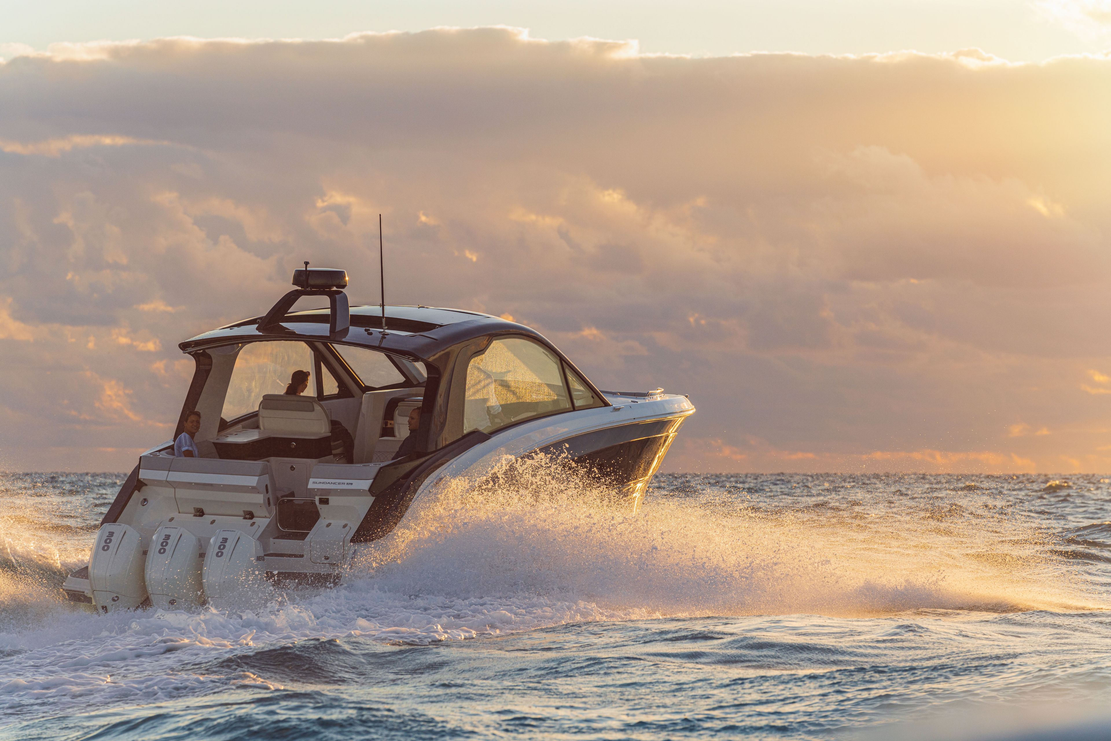 A 2026 Sea Ray Sundancer 370 Outboard cruising on the sea at sunset.