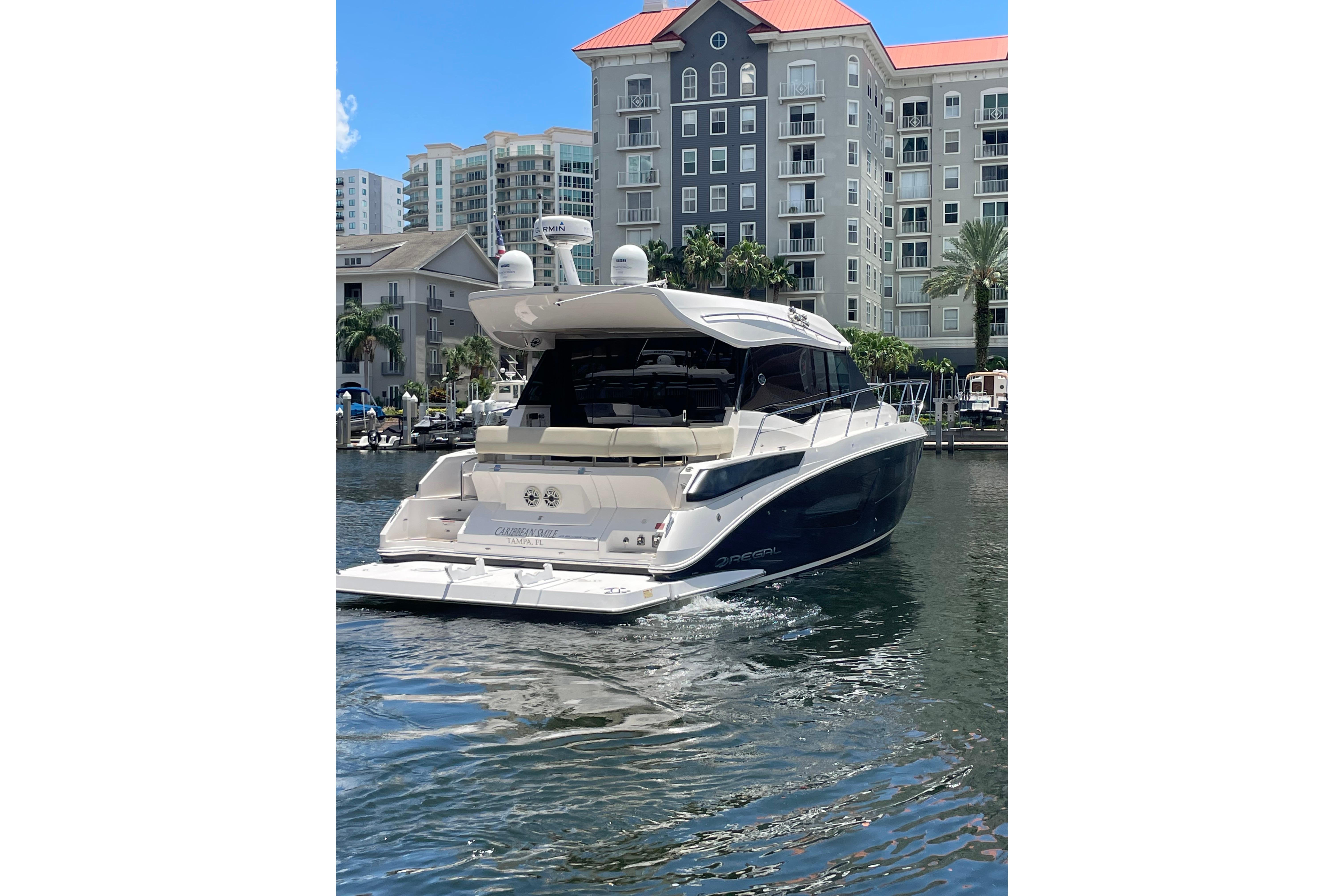 Luxury 2020 Regal 42 Grande Coupe yacht docked near waterfront apartments.
