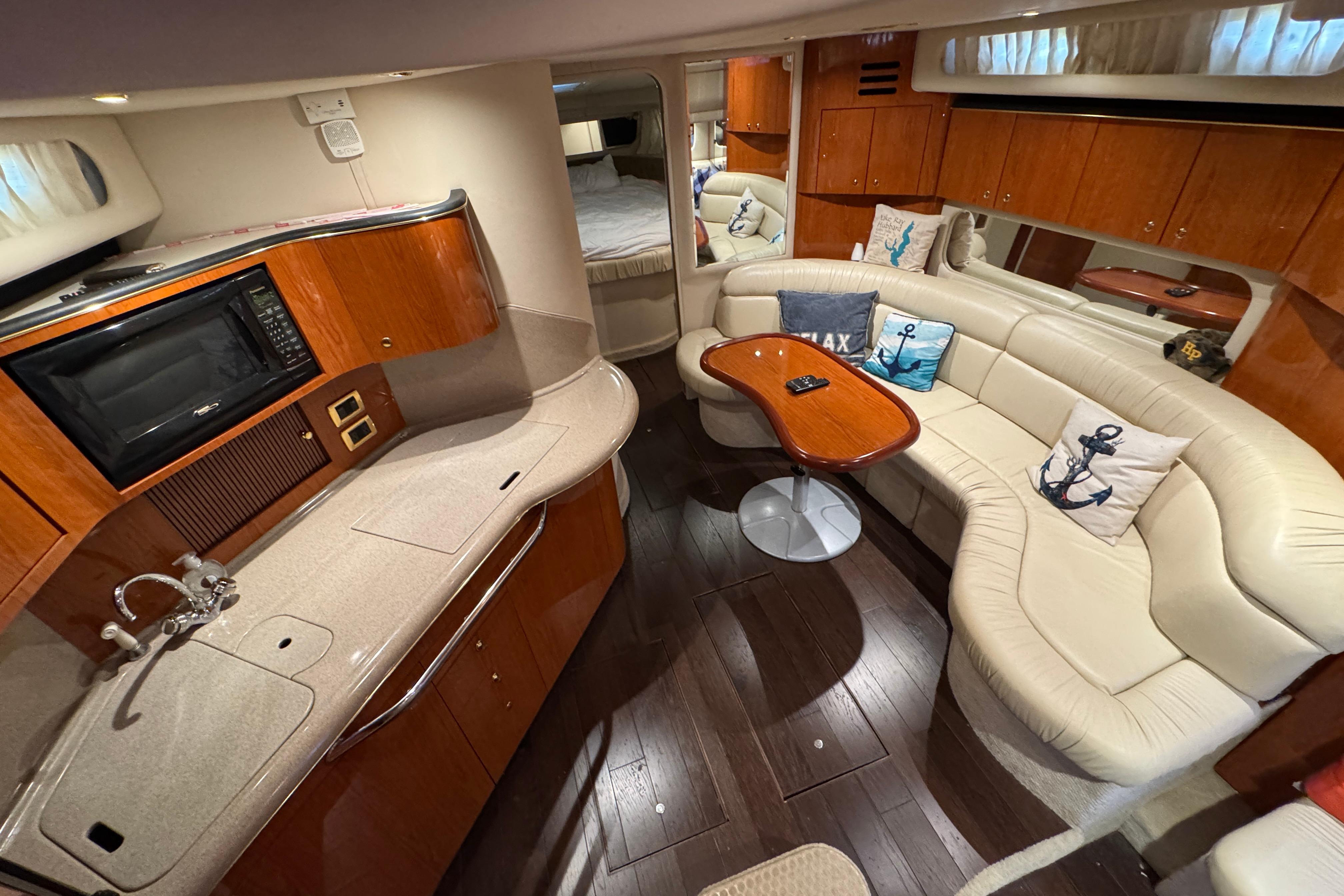 Luxurious interior of 2001 Sea Ray 380 Sundancer yacht with plush seating and kitchenette.